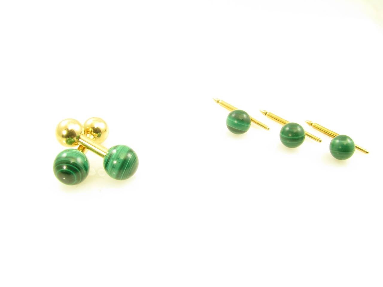 A 14 karat yellow gold and malachite 5 piece “barbell” style dress set, the cufflinks signed Tiffany & Co. 14K.  The set comprises a pair of cufflinks with a malachite ball at one end, and a smaller gold ball at the other end; and 3 malachite and
