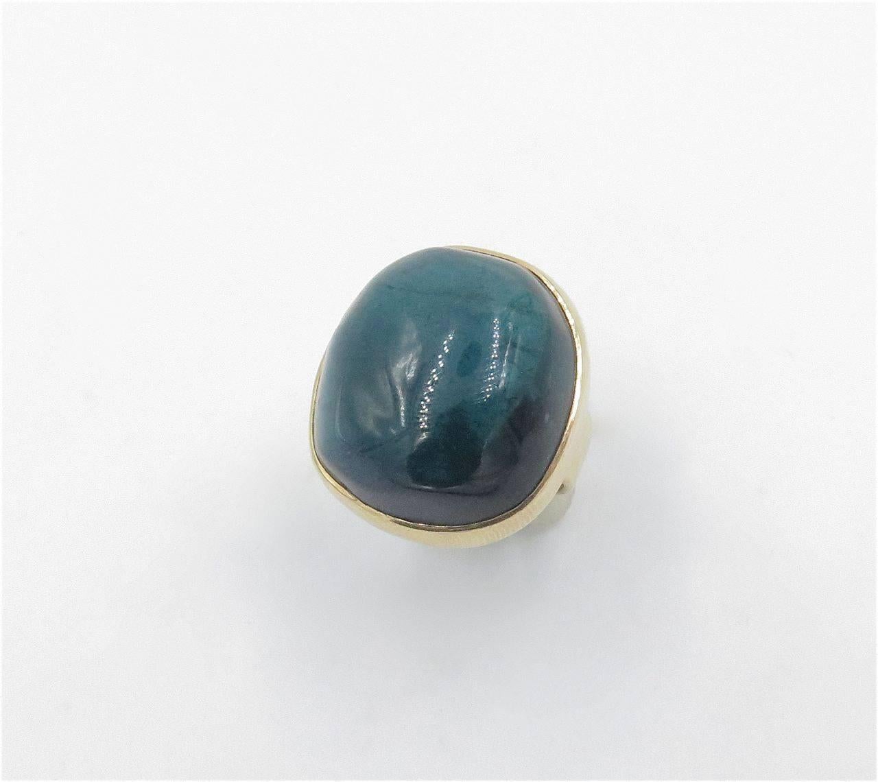 A 14K yellow gold and green tourmaline ring. Circa 1980. Centering a bezel set oval cabochon green tourmaline, measuring approximately 23.00 x 21.00 x 10.50mm, and weighing approximately 40.00 carats. Size 7.  Gross weight approximately 17.7 grams.
