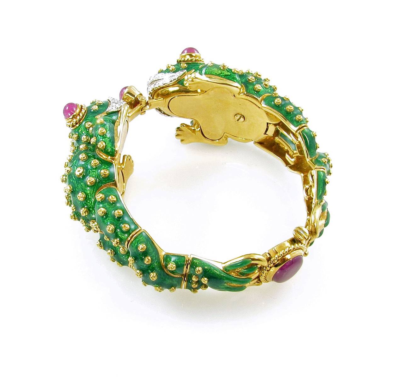 An 18 karat yellow gold, platinum, diamond, ruby and green enamel double frog bracelet, David Webb, Circa 1960s.  Signed Webb 18K Plat.  Designed as two confronting frogs applied with green enamel with gold accents, set with oval-shaped cabochon