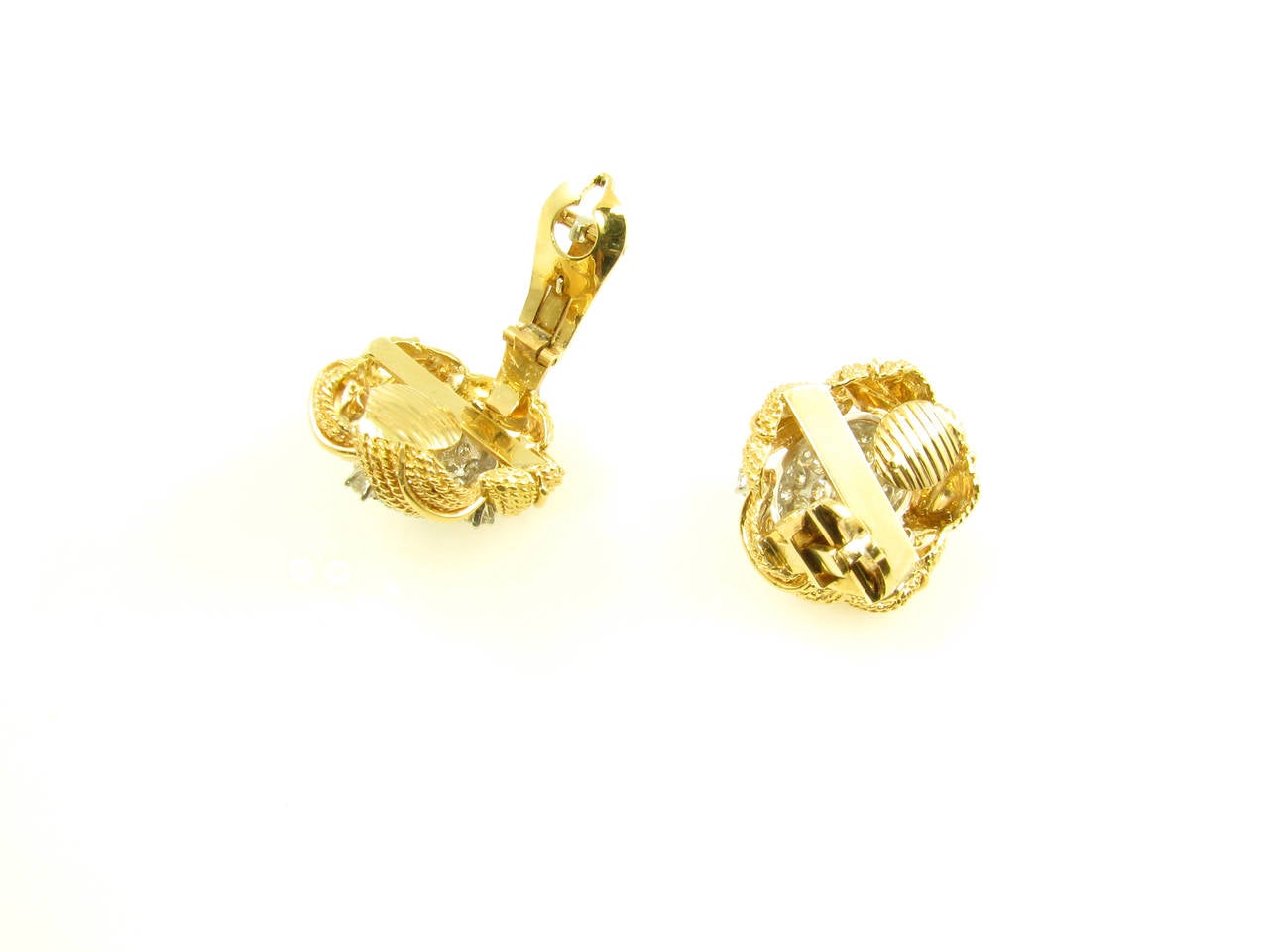 A pair of 18 karat yellow gold, platinum and diamond earrings, Circa 1960.  The earrings are designed with an oval pave diamond set platinum dome in the center, with 5 prong set diamonds set between the 5 yellow gold rope style leaf frame.  The