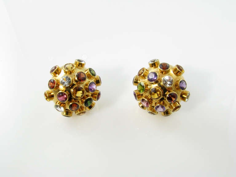 A pair of 18 karat yellow gold “Sputnik” multi colored stone earrings with 14 karat yellow gold clips.  Circa 1950s.  The earrings are of dome shape, each containing 19 bezel set stones consisting of:  aquamarine, citrine, peridot, garnet, amethyst,