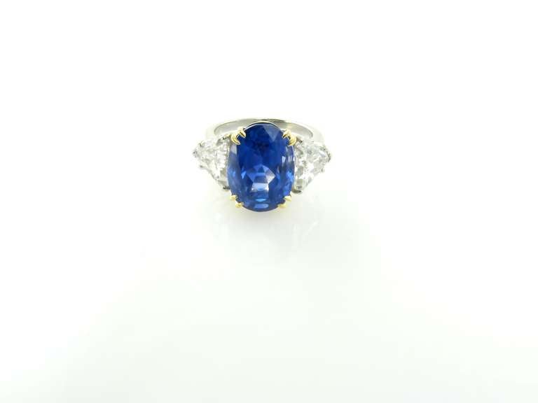 Ein Ring aus Platin und 18-karätigem Gelbgold mit Saphir und Diamant.  Der facettierte ovale Saphir in der Mitte wiegt 10,45 Karat und ist in einer doppelten Zackenfassung aus 18 Karat Gelbgold gefasst.  Die beiden seitlichen Diamanten im