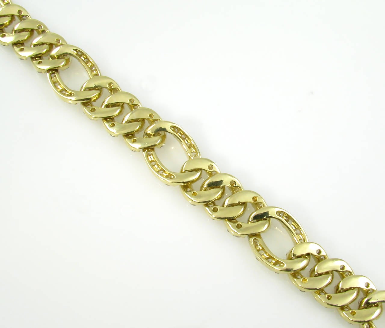 An 18 karat yellow gold and diamond flexible link bracelet, Circa 1980s.  The bracelet is designed as a larger oval link alternating with 3 smaller links.  Each link is prong set with round brilliant cut diamonds.  The bracelet contains a total of
