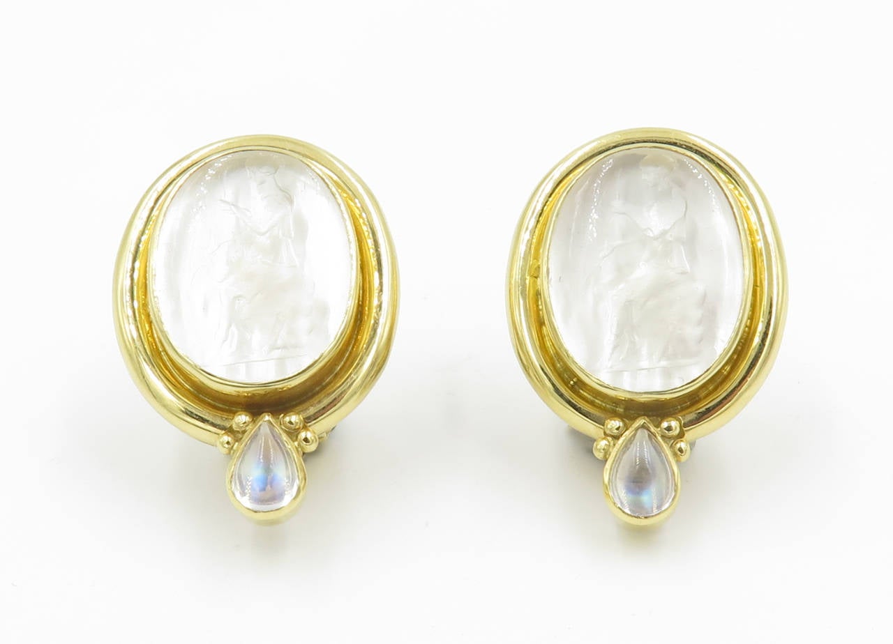 A pair of 18 karat yellow gold, Venetian glass intaglio on mother-of-pearl, and cabochon pear shaped moonstone earrings, Elizabeth Locke, Circa 1990s.  The intaglios are carved with a seated figure with a bow.  The earrings have a gross weight of