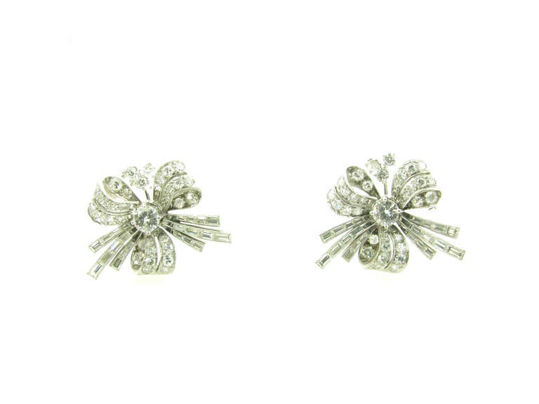 A pair of Art Deco platinum and diamond earrings with 14 karat white gold earclips, circa 1930s.  The earrings are in the shape of stylized bows.  The centers each set with a round brilliant cut diamond weighing approximately .31 carat, each is pave