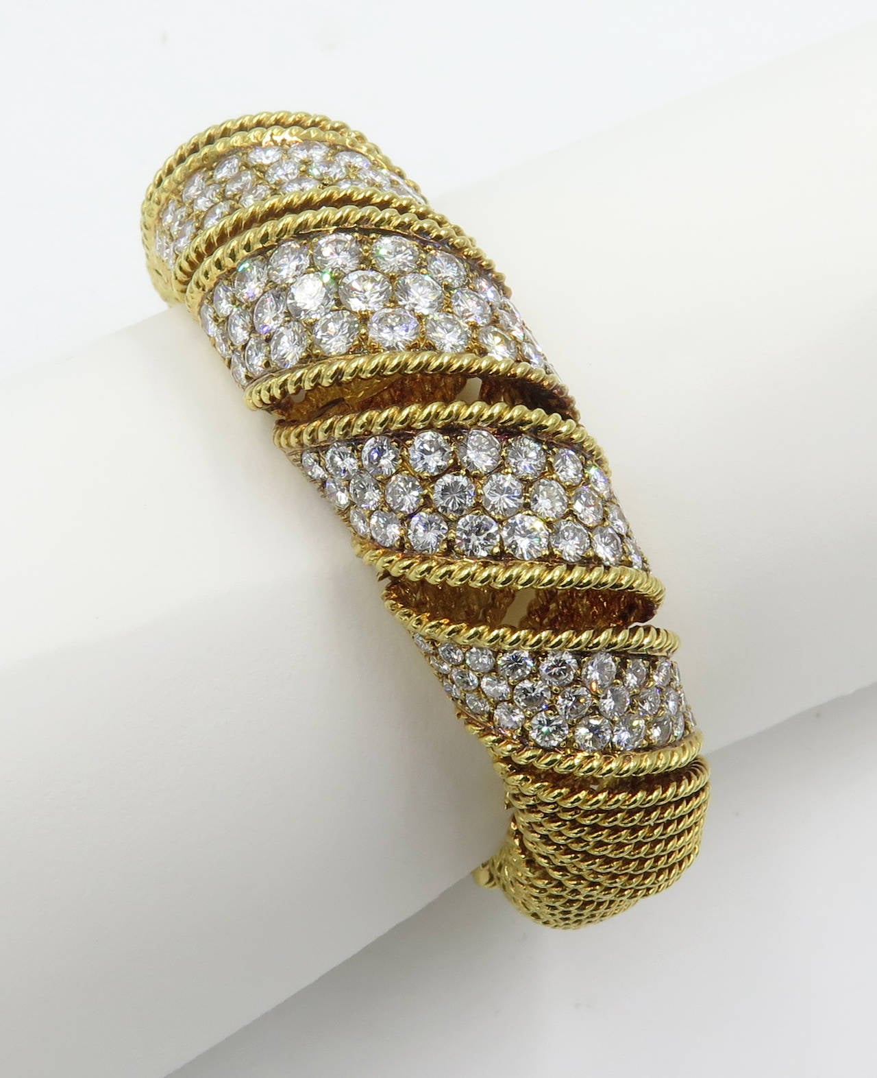 An 18 karat yellow gold and diamond bracelet, Signed Modele Sterle Paris 18K © montreaux, Circa 1960s.  The bracelet is designed as  graduated sections of spiraling gold rope, the 5 graduated center sections set with a total of 141 round brilliant