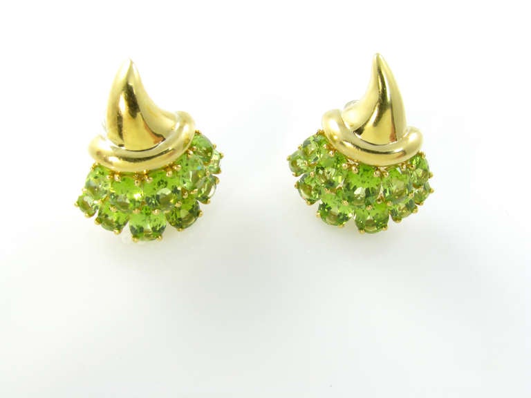 A pair of 18 karat yellow gold and peridot Cornucopia earrings, Verdura, circa 1980s.  Signed Verdura 750 and Italian maker’s mark.  The earrings are each in the shape of a cornucopia with yellow gold horn of plenty and 2 rows of oval faceted prong