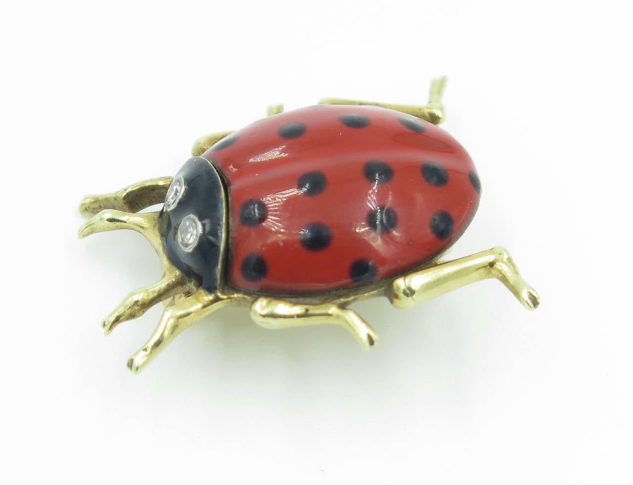 A 14 karat yellow gold, enamel and diamond ladybug brooch.  Cartier.  Signed 14K Cartier 10205.  The body is enameled red with black dots the eyes are each collet set with a single cut diamond.  The brooch has a gross weight of approximately 9.4