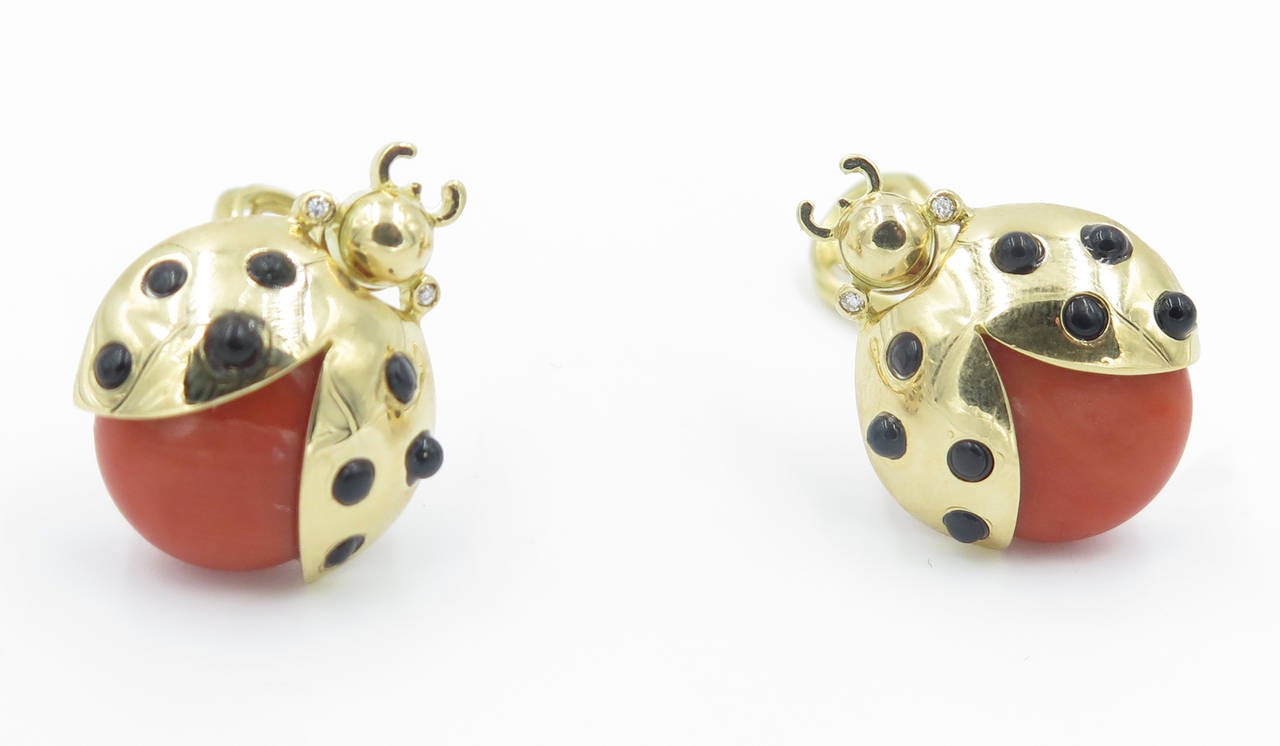 A pair of 18 karat yellow gold, coral, black onyx and diamond earrings.  Loffredo.  The earrings are designed as ladybugs with coral body and gold wings set with cabochon black onyx.  The earrings have a gross weight of approximately 15.6 grams and