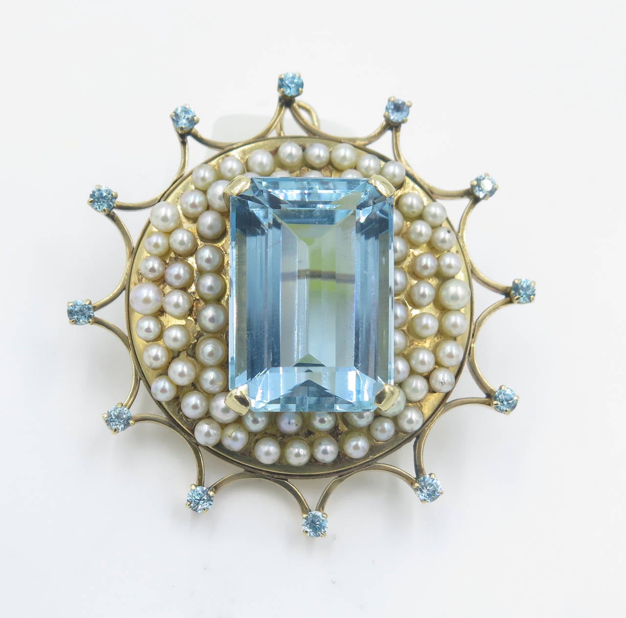 A yellow gold, aquamarine and pearl brooch. Circa 1940s. The circular brooch is set with an aquamarine in the center weighing approximately 31.80 carats, in a mount set with numerous random sized cultured pearls, the frame is set with 12 round