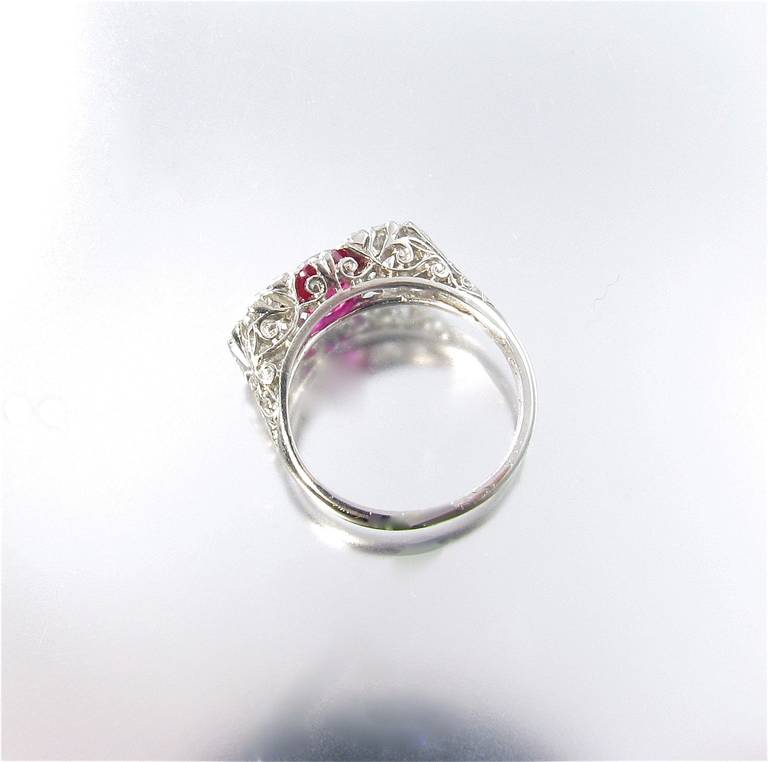 An Edwardian platinum, ruby and diamond 3 stone ring, circa 1910.  The platinum filigree mount is set with a center ruby weighing 1.51 carats, flanked by two (2) old European cut diamonds weighing .51 and .50 carats.  Note:  all stones weighed