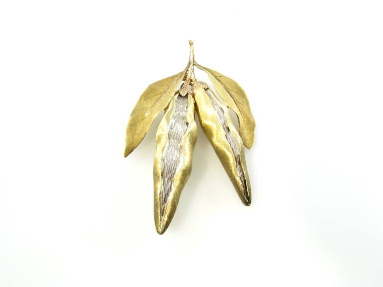 An 18 karat yellow and white gold brooch in the style of a double pea pod, by Buccellati, Italy, circa 1970s.  The brooch has a gross weight of approximately 36.8 grams and measures 3 inches long.
