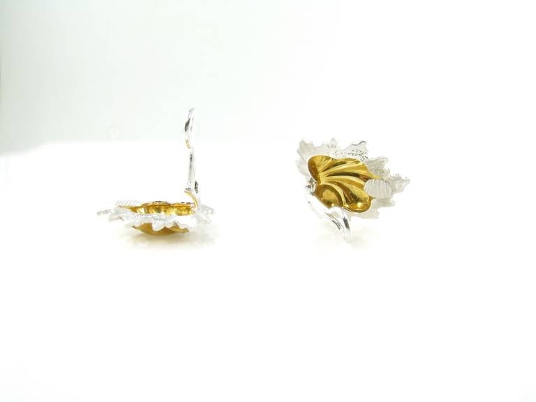 A pair of 18 karat yellow and white gold stylized leaf form earrings by Buccellati, Italy circa 1970s.  The earrings are designed with a lobed yellow gold center with a white gold textured frame.  The earrings have a gross weight of approximately