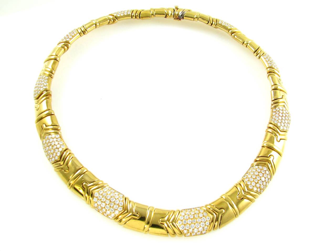 An 18 karat yellow gold and diamond necklace, Signed Bulgari Roma BA163, circa 1990s.  The flexible choker necklace is set with alternating geometric gold and pave diamond sections.  The 17 pave round brilliant cut diamond set sections contain a