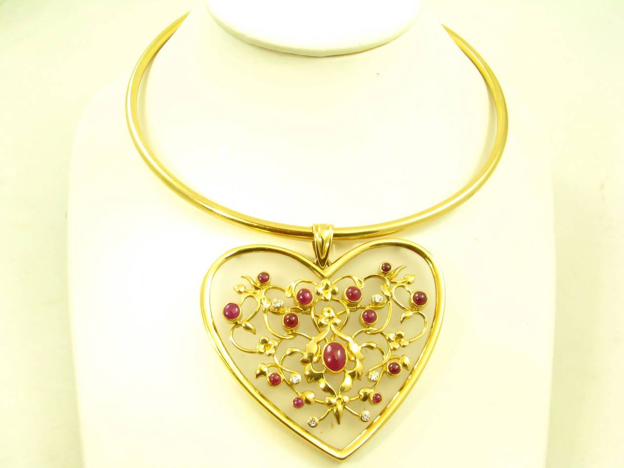 An 18 karat yellow gold , ruby and diamond frosted rock crystal pendant suspended from an 18 karat yellow gold neckwire, by Ilias Lalaounis, Greece, circa 1980s.  The pendant is set with 13 cabochon rubies and 6 round brilliant cut diamonds, the 6