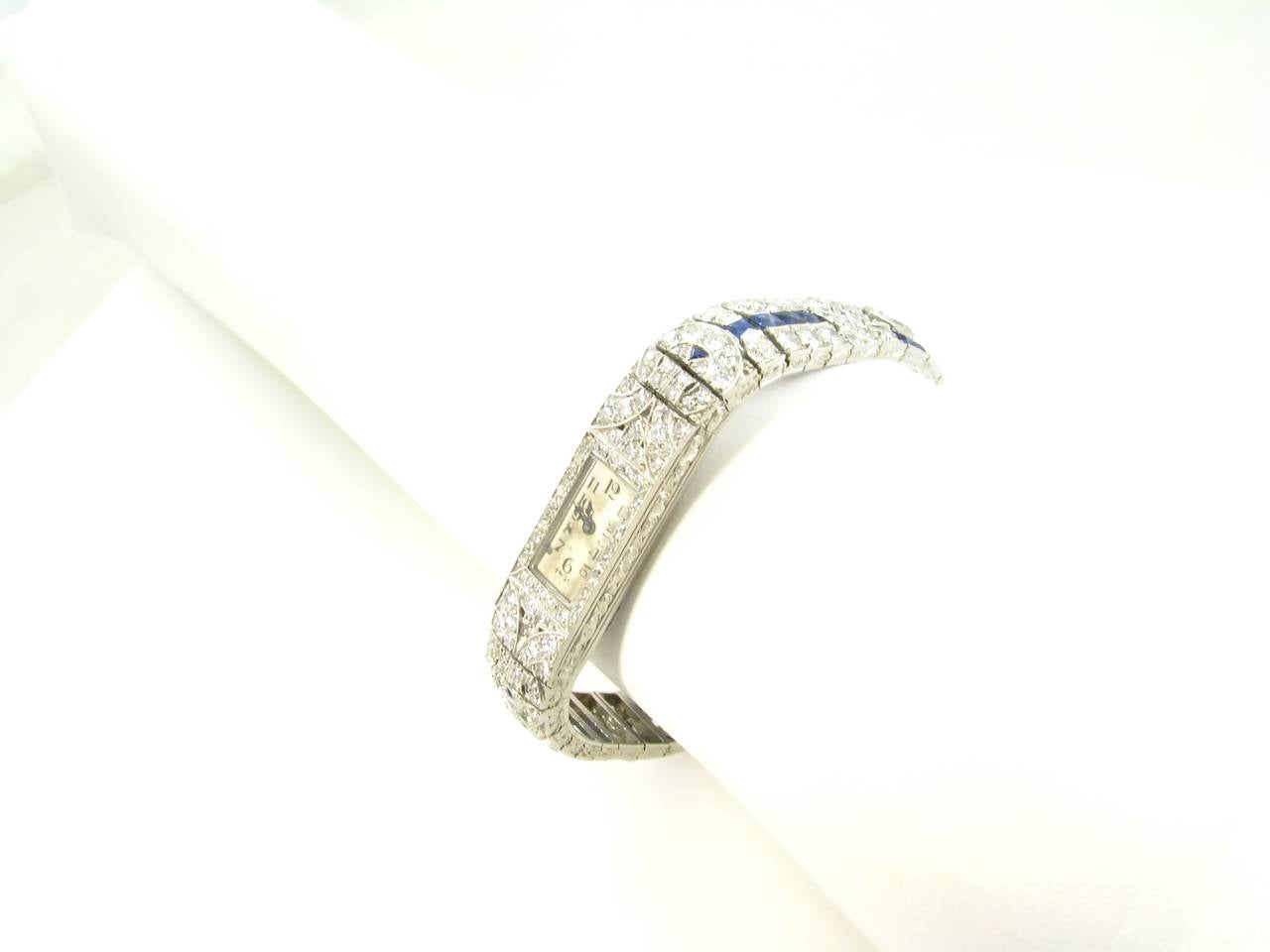 An Art Deco, platinum, sapphire and diamond watch, Jaeger LeCoultre.  The bracelet style watch is set with 2 elongated hexagonal cut diamonds weighing a total of approximately 1.10 carats, 220 single cut and transitional cut diamonds weighing a