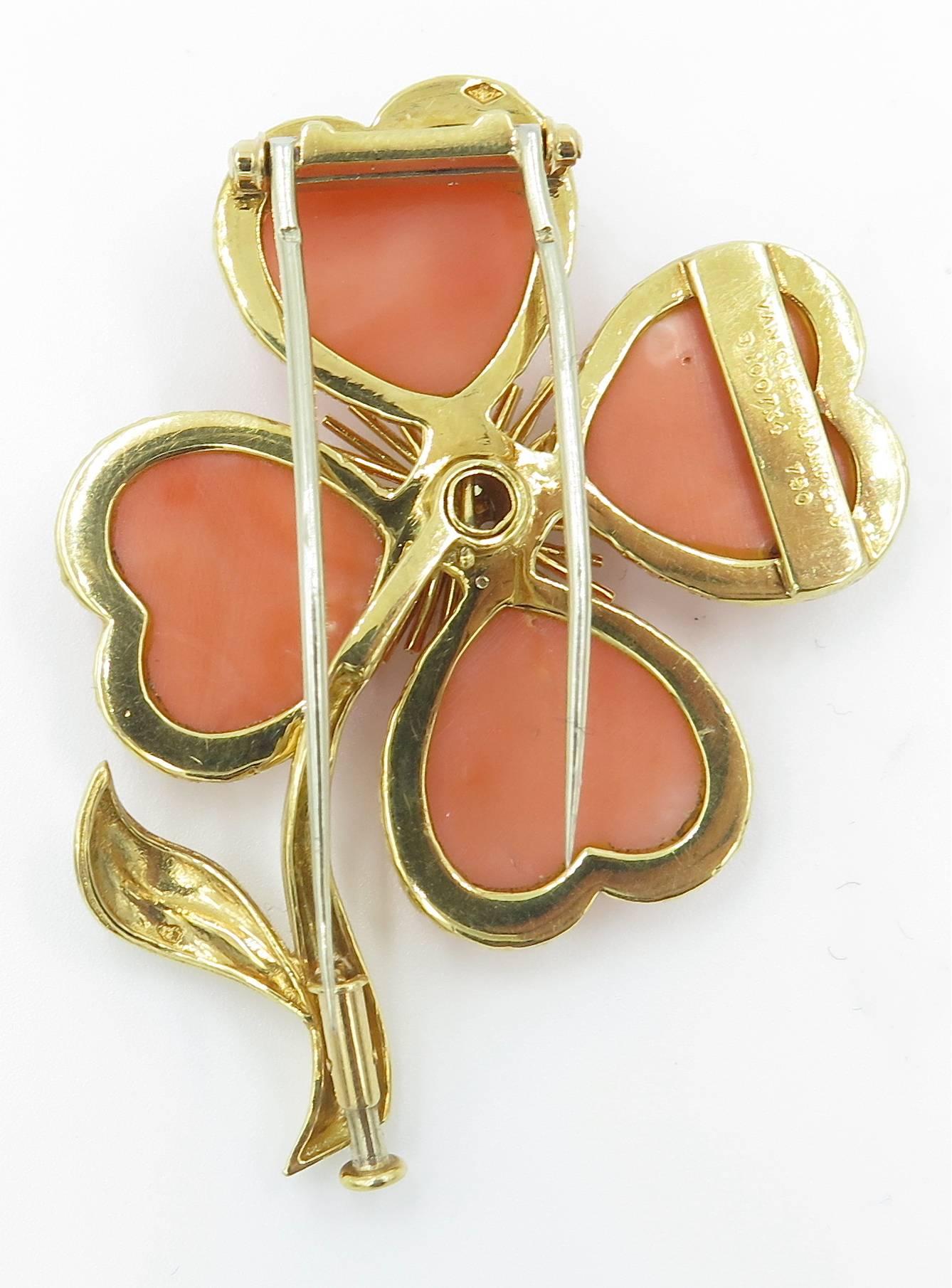 An 18 karat yellow gold, coral and diamond “Cosmos” brooch, Van  Cleef & Arpels. Circa 1960. Numbered B 10074K. Designed as four leaf clover, extending carved heart-shaped coral petals, centering a round brilliant-cut diamond pistill, enhanced by a
