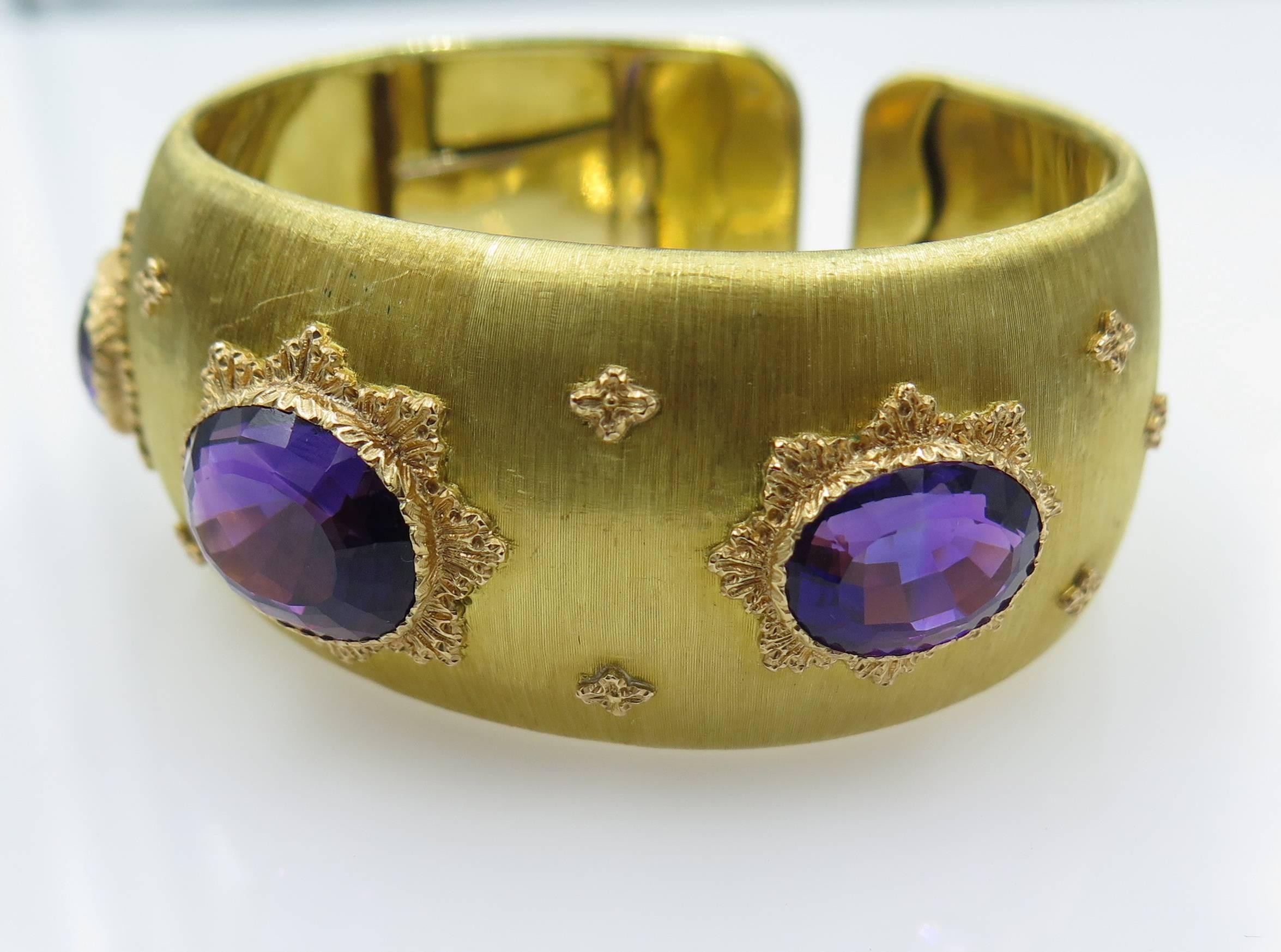 An 18 karat gold and amethyst bracelet, Buccellati, Italian. Designed as a textured gold hinged cuff, centering three oval-cut amethysts, measuring from approximately 13.70 x 10.00 x 7.30 to 16.00 x 12.50 x 10.00 mm and weighing approximately 5.50,