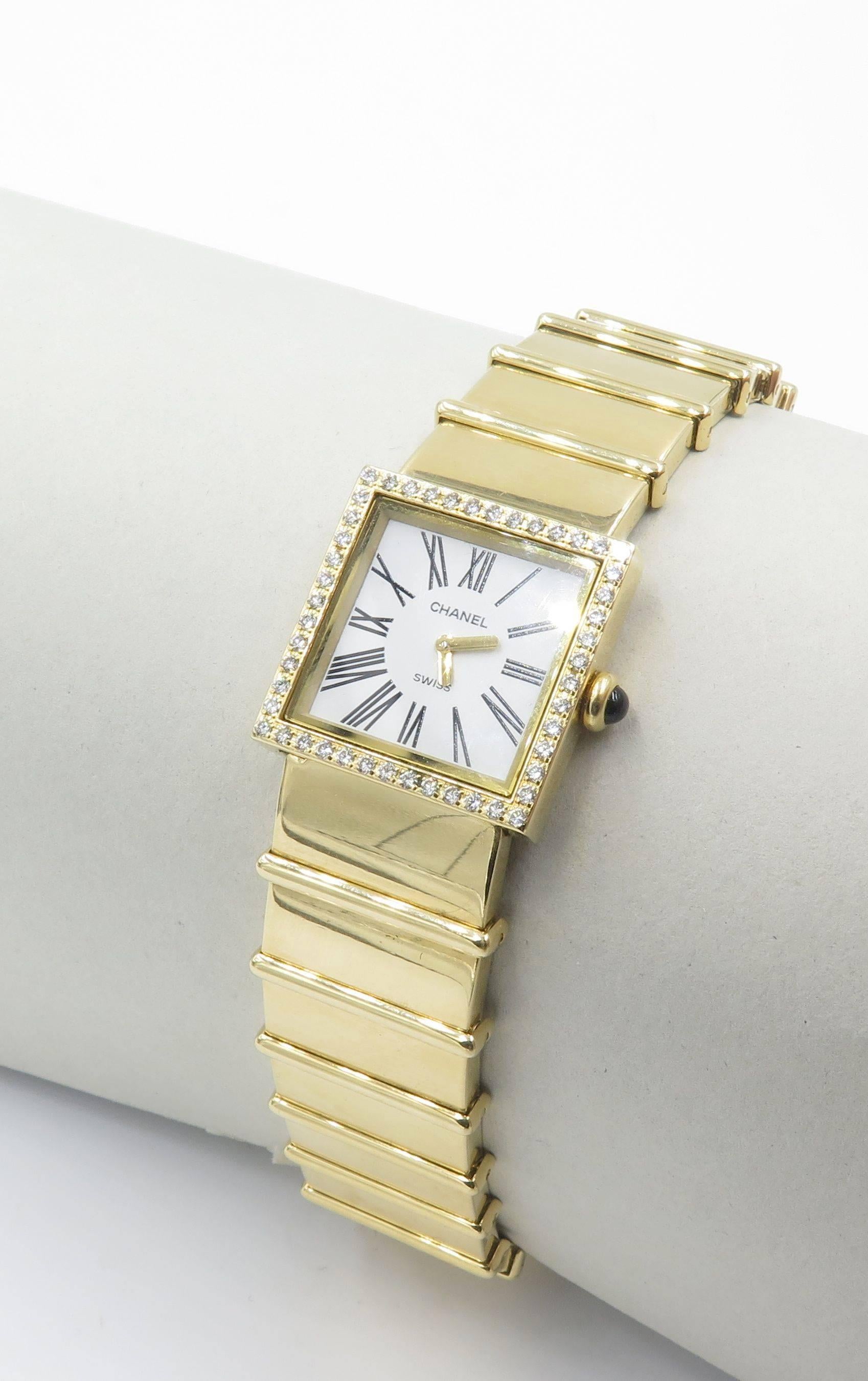 An 18 karat yellow gold and diamond ladies wristwatch.  Chanel.  The ladies yellow gold 23 mm vintage Chanel Mademoiselle Diamond Swiss made quartz watch is set with a diamond bezel, white flat dial, black Roman numeral hour markers, gold-tone stick