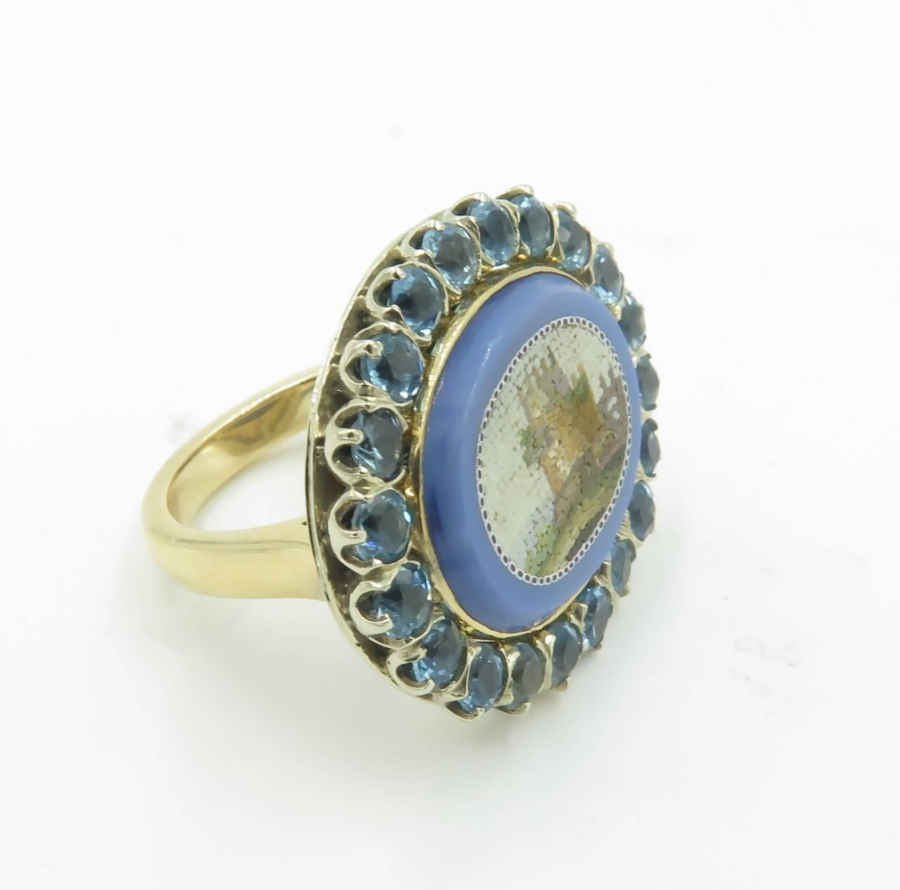 An antique Vatican School micromosaic depicting the Torre Normana, 19th Century, in a contemporary 14 karat white and yellow gold ring mount designed by Marcella Ciceri.  The micromosaic is set in the original oval medium blue glass surround, within