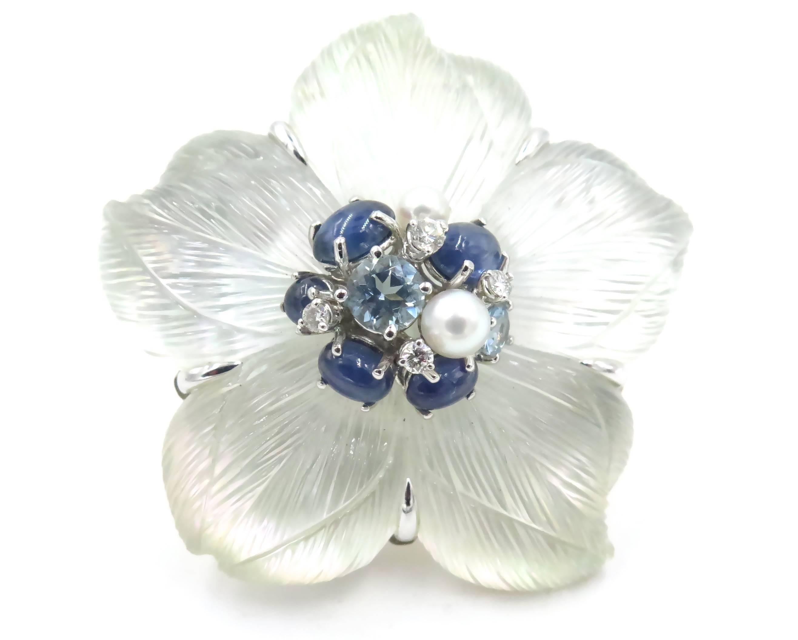 An 18 karat white gold, carved rock crystal, mother of pearl, cultured pearl, cabochon sapphire, aquamarine and diamond brooch.  Seaman Schepps.  Circa 1980.  The brooch is known as the Clematis.  Signed on the reverse Seaman Schepps 18214.  Gross