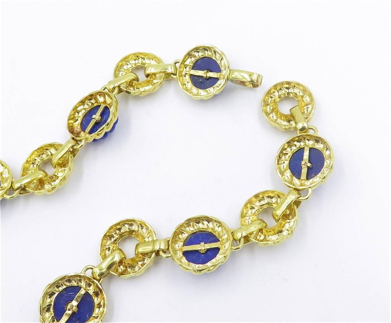 An 18 karat yellow gold and lapis lazuli necklace and matching earrings.  Trio.  Circa 1970. The necklace is designed as a long chain, comprised of hammered gold circular links, spaced by carved lapis lazuli floret plaques, each centering a gold