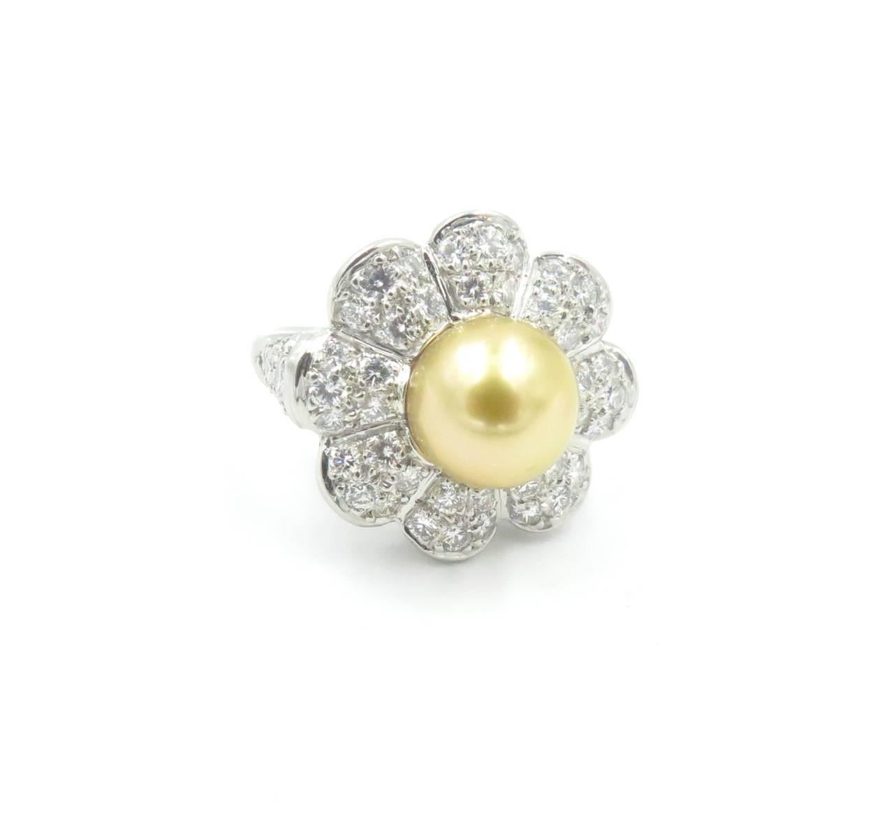 A platinum, diamond and 9.5 mm golden pearl ring.  The ring is designed with a center pearl, set in a lobed pave diamond flower form mount with diamonds on each shoulder.  The ring contains a total of 54 round brilliant cut diamonds weighing a total