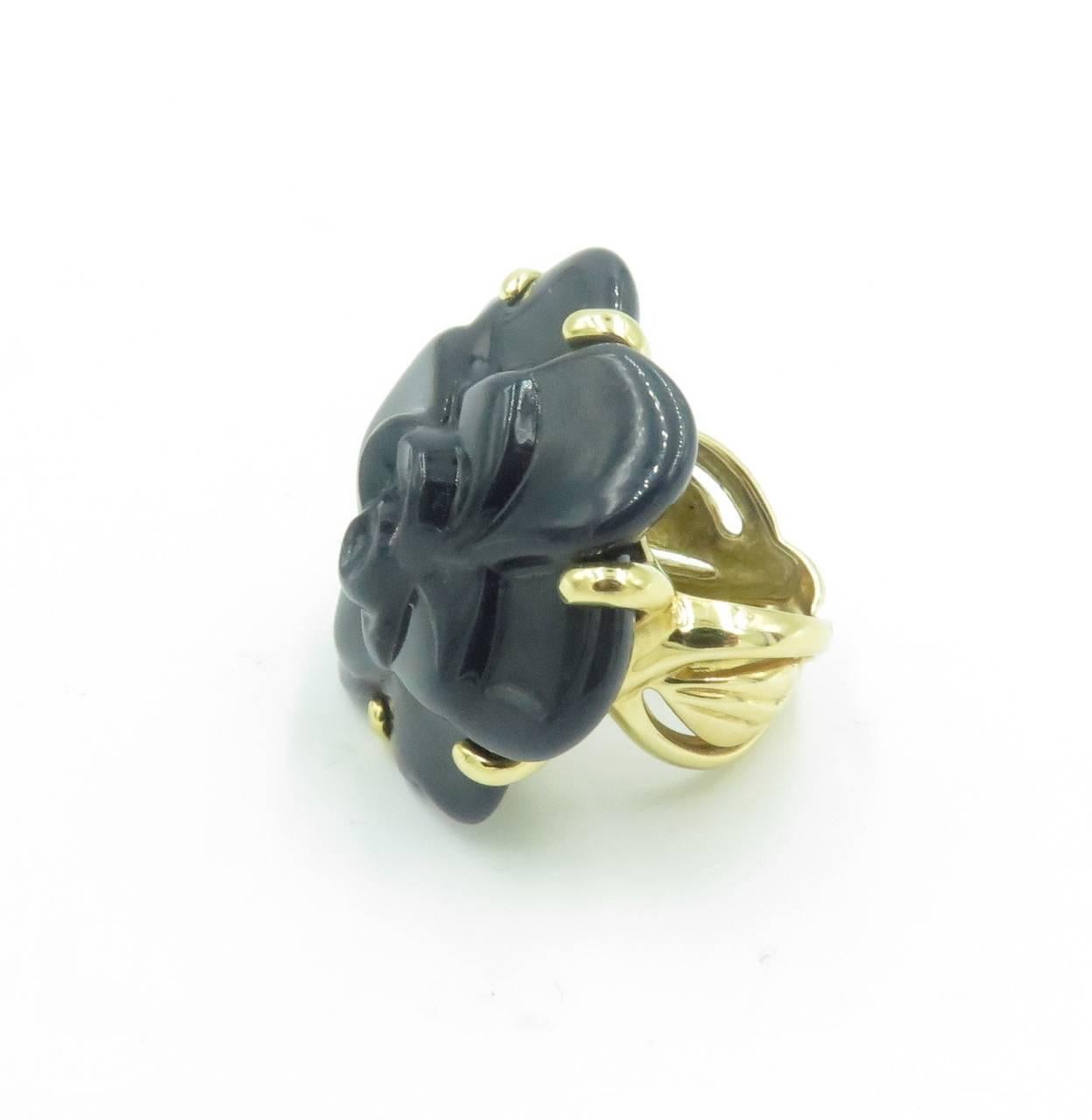 An 18 karat yellow gold and onyx medium size Camelia ring. Chanel. French. Circa 2000. Set with a carved onyx flowered, with undulating twisted gold shank. Size 4 1/2. Gross weight is approximately 19.2 grams. Stamped Chanel, 750, with French assay