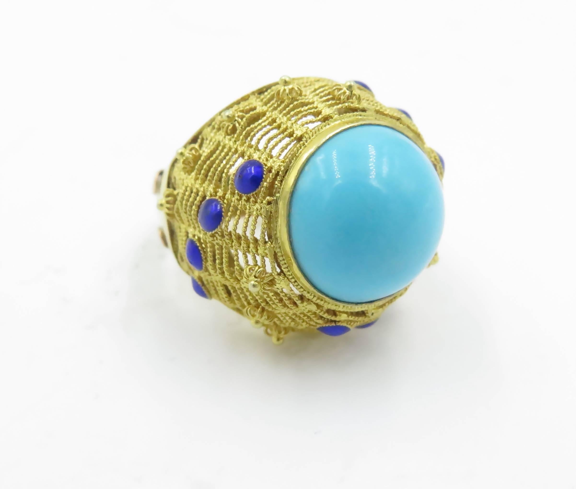 A 14 karat yellow gold, turquoise and lapis lazuli ring. Circa 1970.  Of openwork bombe design, centering a round cabochon turquoise, measuring approximately 15.00mm, enhanced by small cabochon lapis lazuli. Approximately size 6  (with sizer). Gross