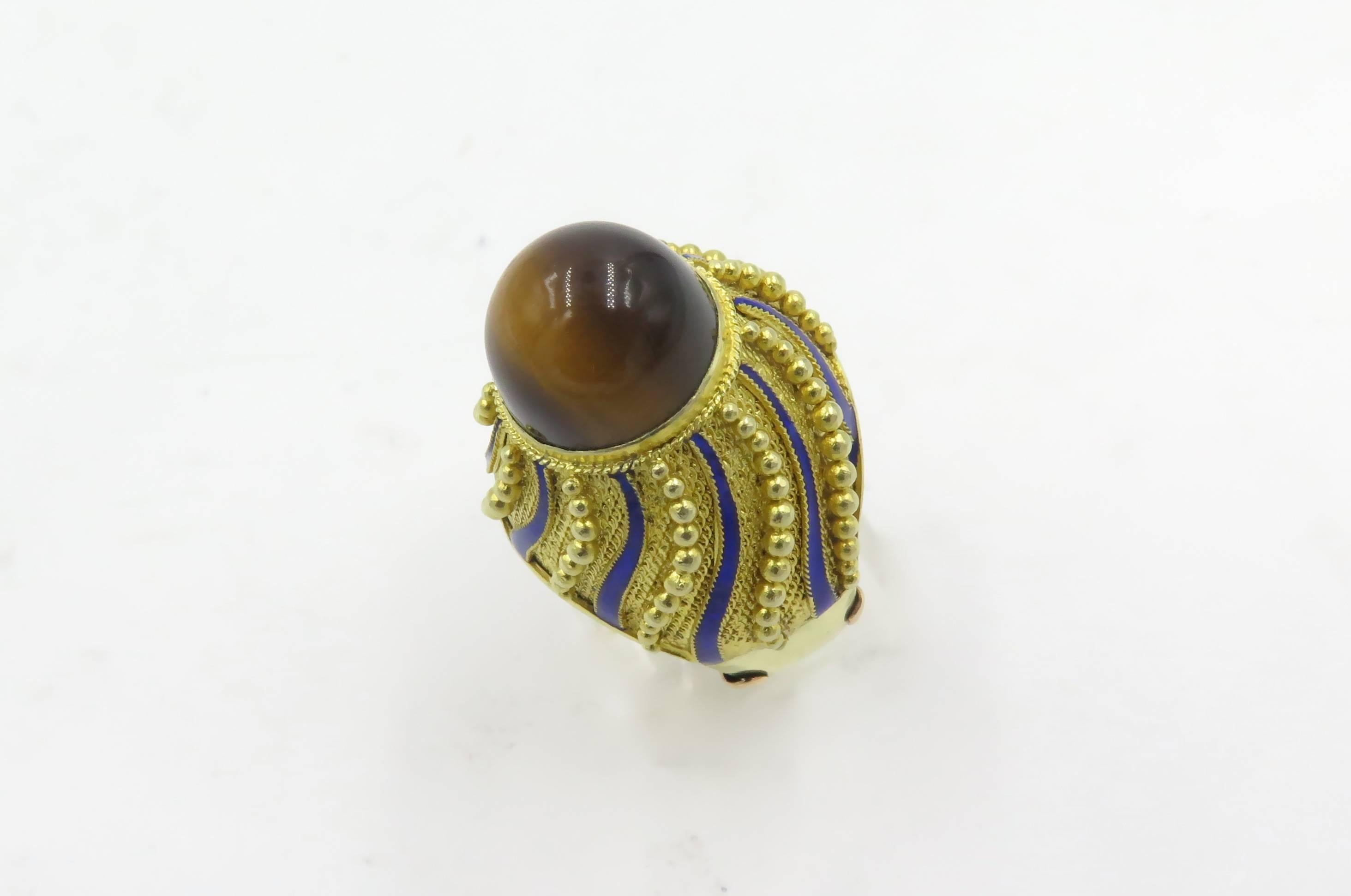 A 14 karat yellow gold, tigers eye and blue enamel ring.