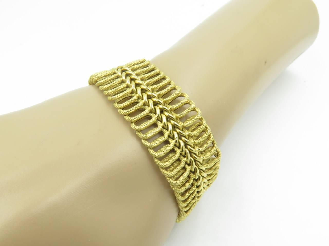 An 18 karat yellow gold bracelet.  Italian. The flexible band is composed of two rows of interlocking textured oval links, centering a polished gold braid. Length is approximately 7 1/4 inches.  Gross weight is approximately 33.6 grams. Stamped