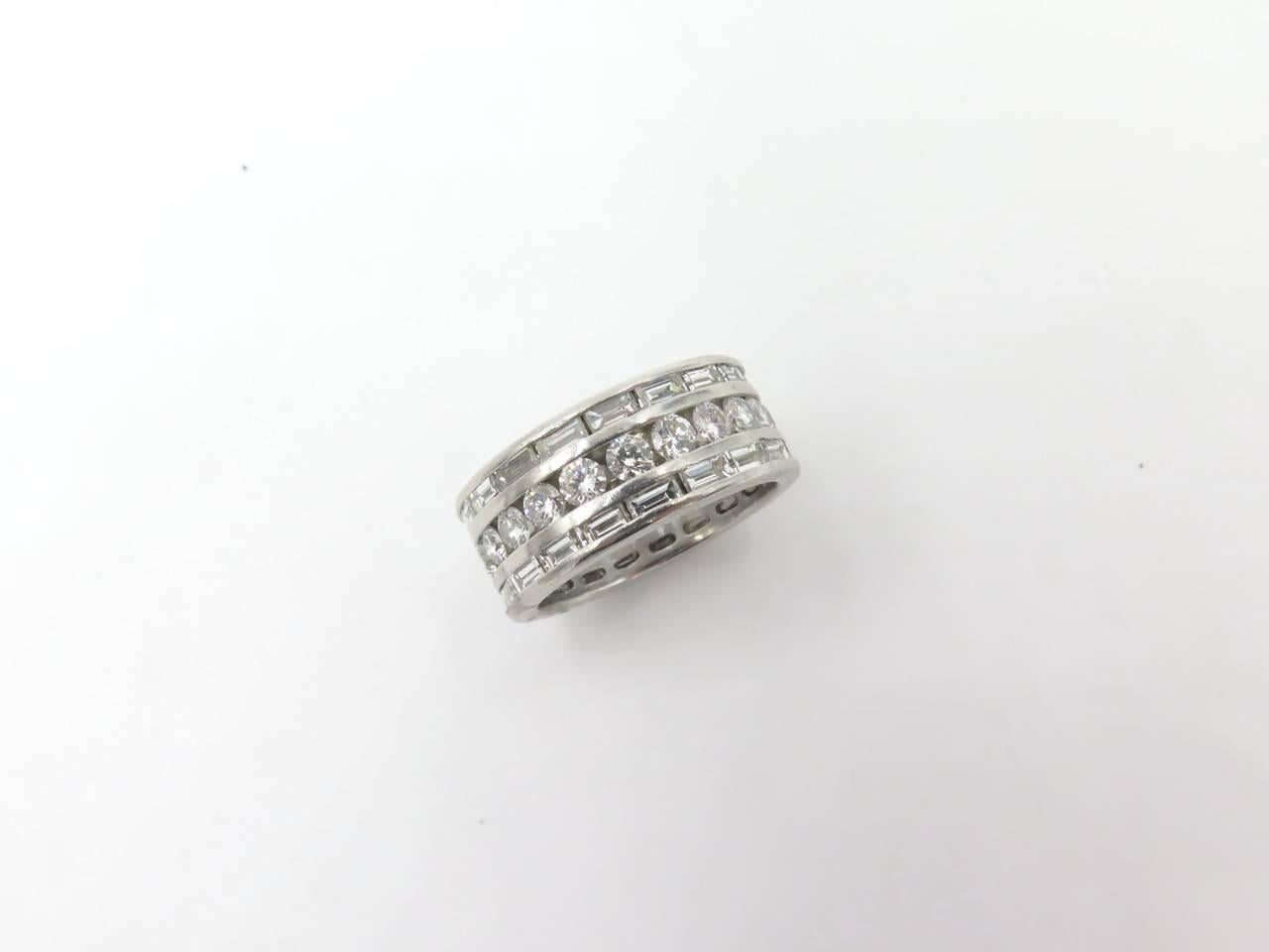 A platinum and diamond triple row band. Cenering a row of circlar cut diamonds, flanked by a row of baguette cut diamonds. Twenty two (2) circular and thirty six baguette weigh approximately 3.00 carats total. Approximately size 6. Gross weight is