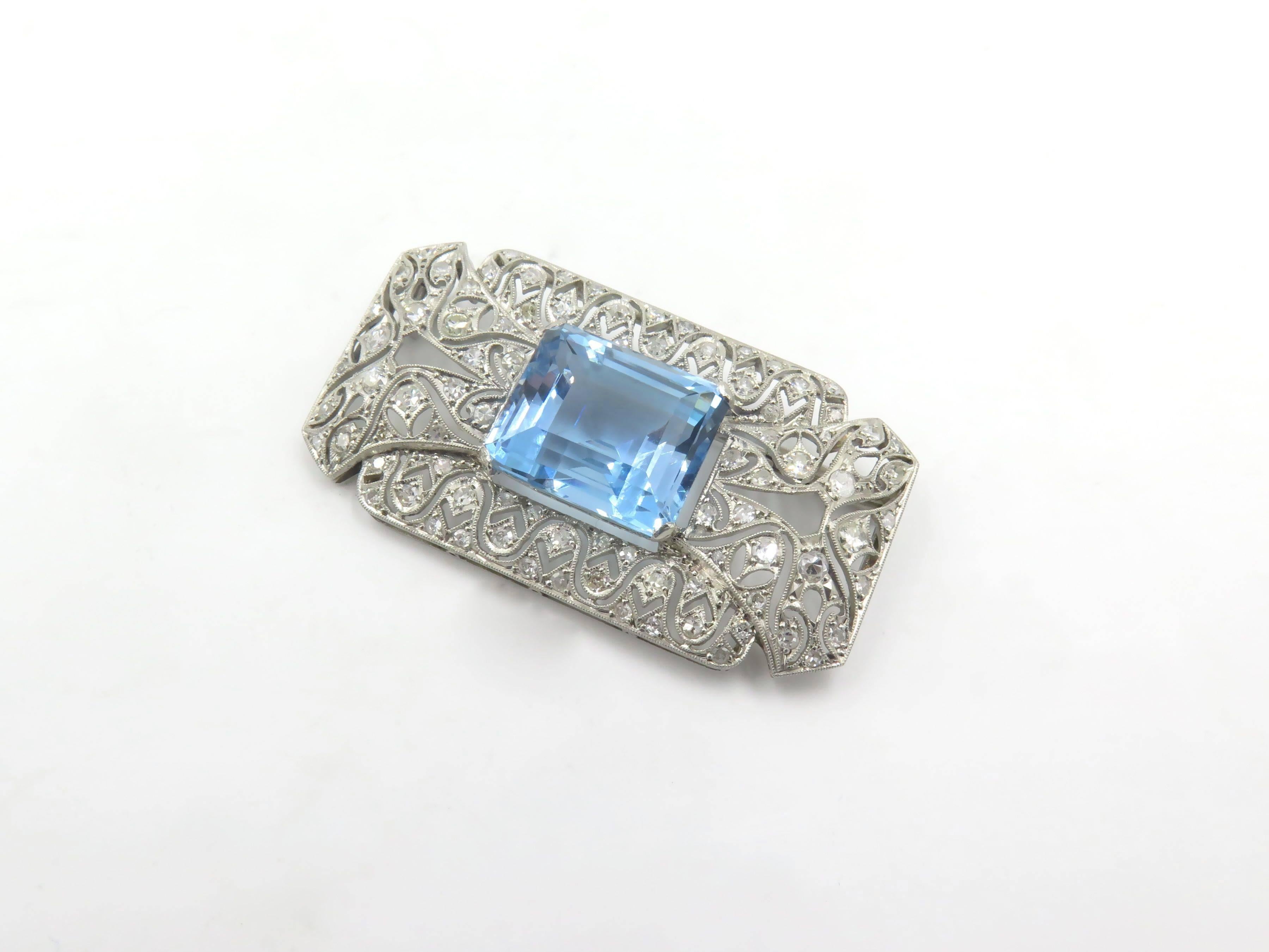 A platinum, aquamarine and diamond brooch. Circa 1930. Designed as a rectangular pierced and openwork circular-cut diamond plaque, centering an emerald cut aquamarine, measuring approximately 15.50 x 13.10 x 10.00mm, and weighing approximately 15.00