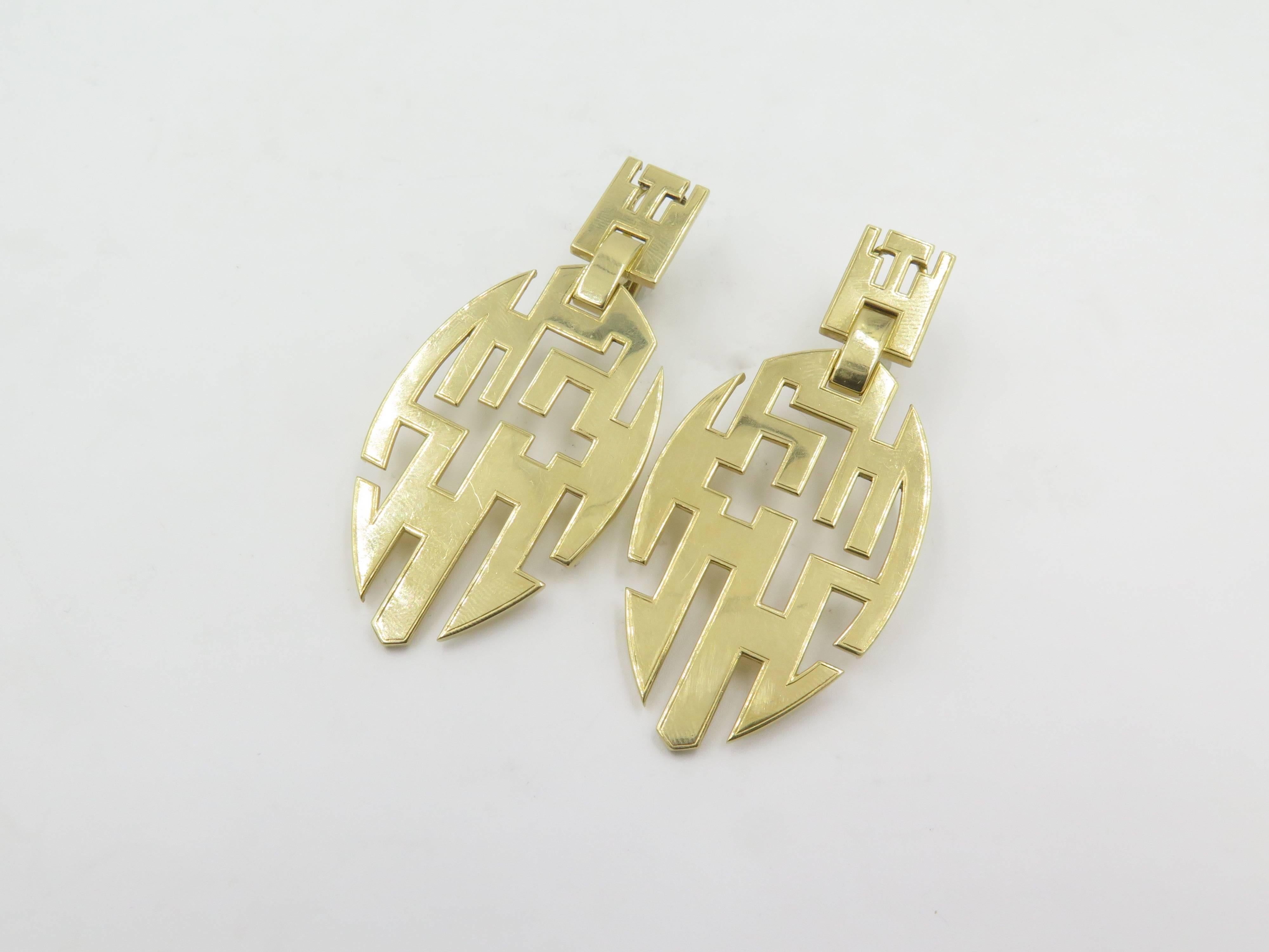 A pair of 18 karat yellow gold earrings.  Cartier.  Circa 1970.  Each designed as a drop shape plaque, with a geometric cut out pattern, from a similarly designed surmout. Signed Cartier numbr 9573. Length is approximately 2 3/4. Gross weight is