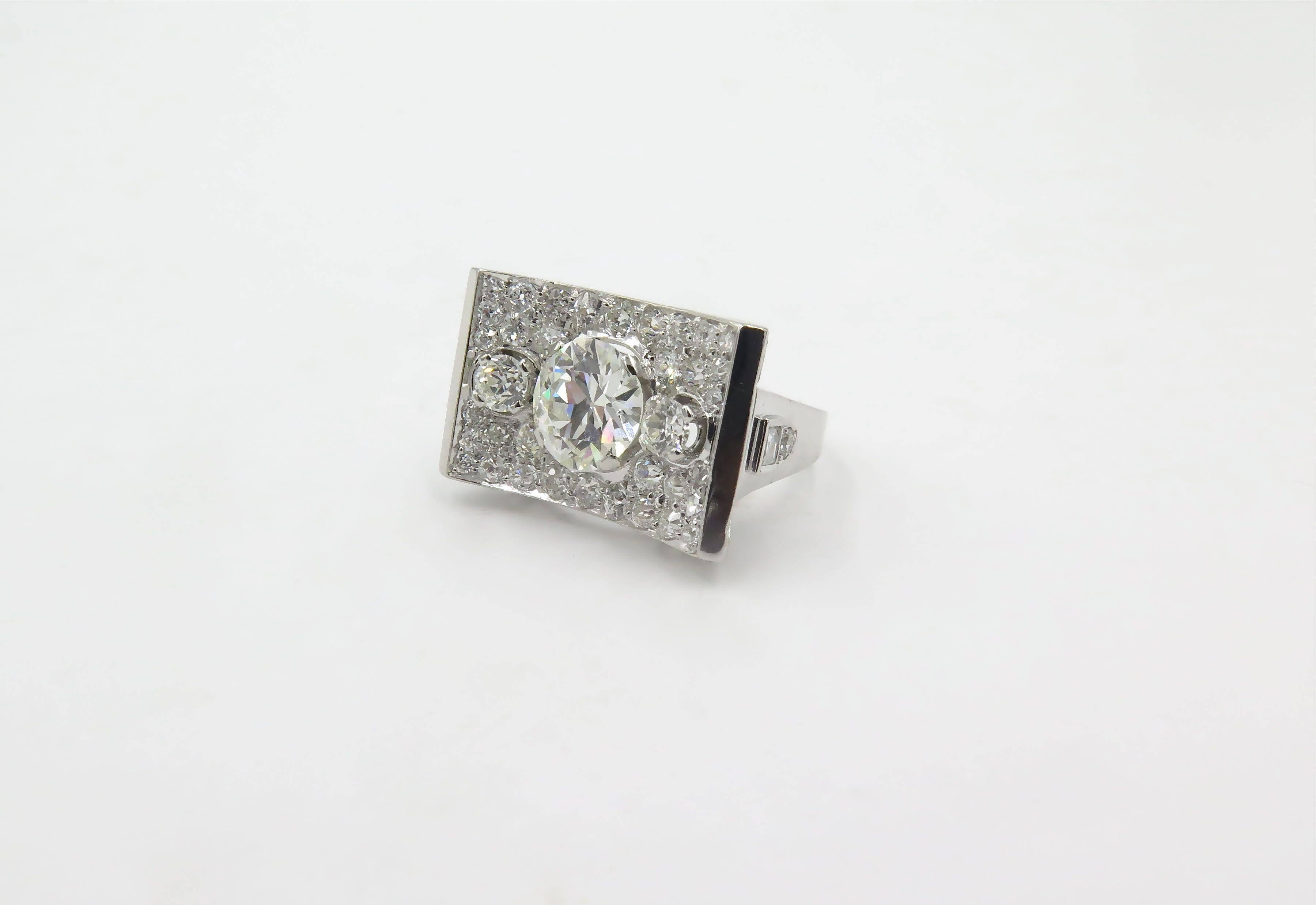 An Art Deco, platinum and diamond ring.  Circa 1930.   Brock.  The ring centers a circular brilliant diamond weighing 1.39 carats, further set with (2) two square cut diamonds and (36) thirty six old mine cut diamonds totaling approximately 2.00