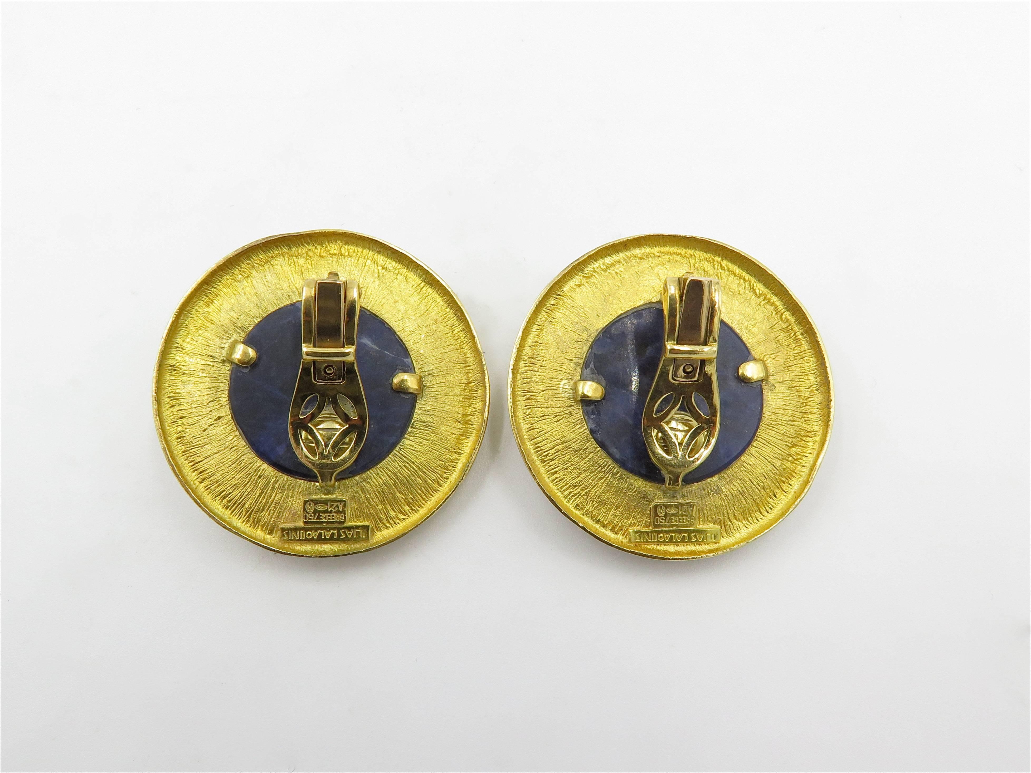 A pair of 18 karat yellow gold and sodalite earrings. Lalaounis. Each set with a round cabochon sodalite, within a matte and polished gold surround. Diameter is approximately 1 1/2 inches. Gross weight is approximately 46.0 grams.