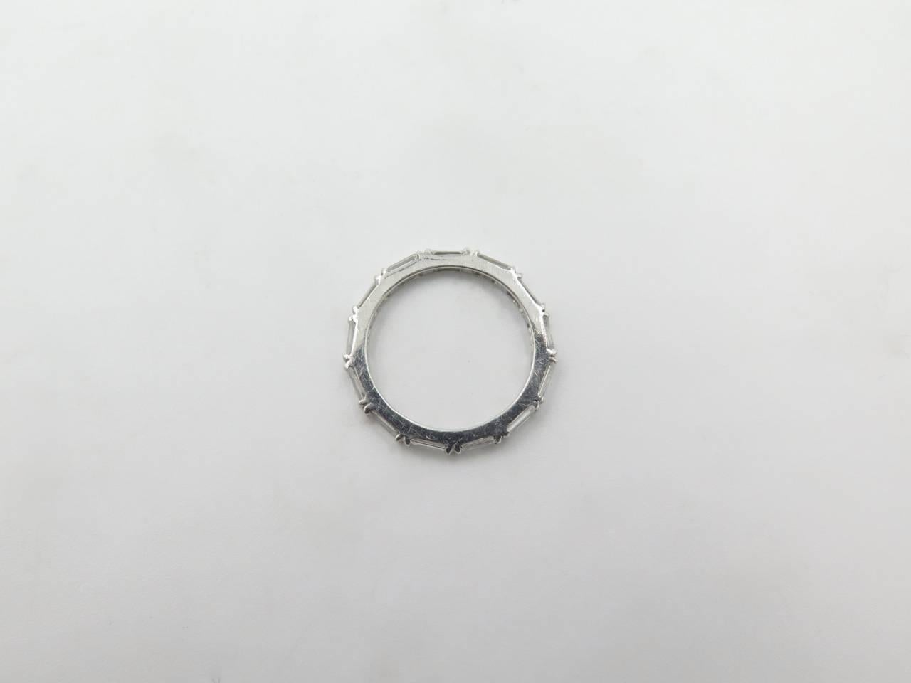 A platinum and diamond ring.  The eternity style band has (13) baguette shape diamonds set in a platinum split bar mounting.  Total diamond weight approximately 1.06 carats, 2mm in width.  Gross weight approximately 2.4 grams.  Size 5.