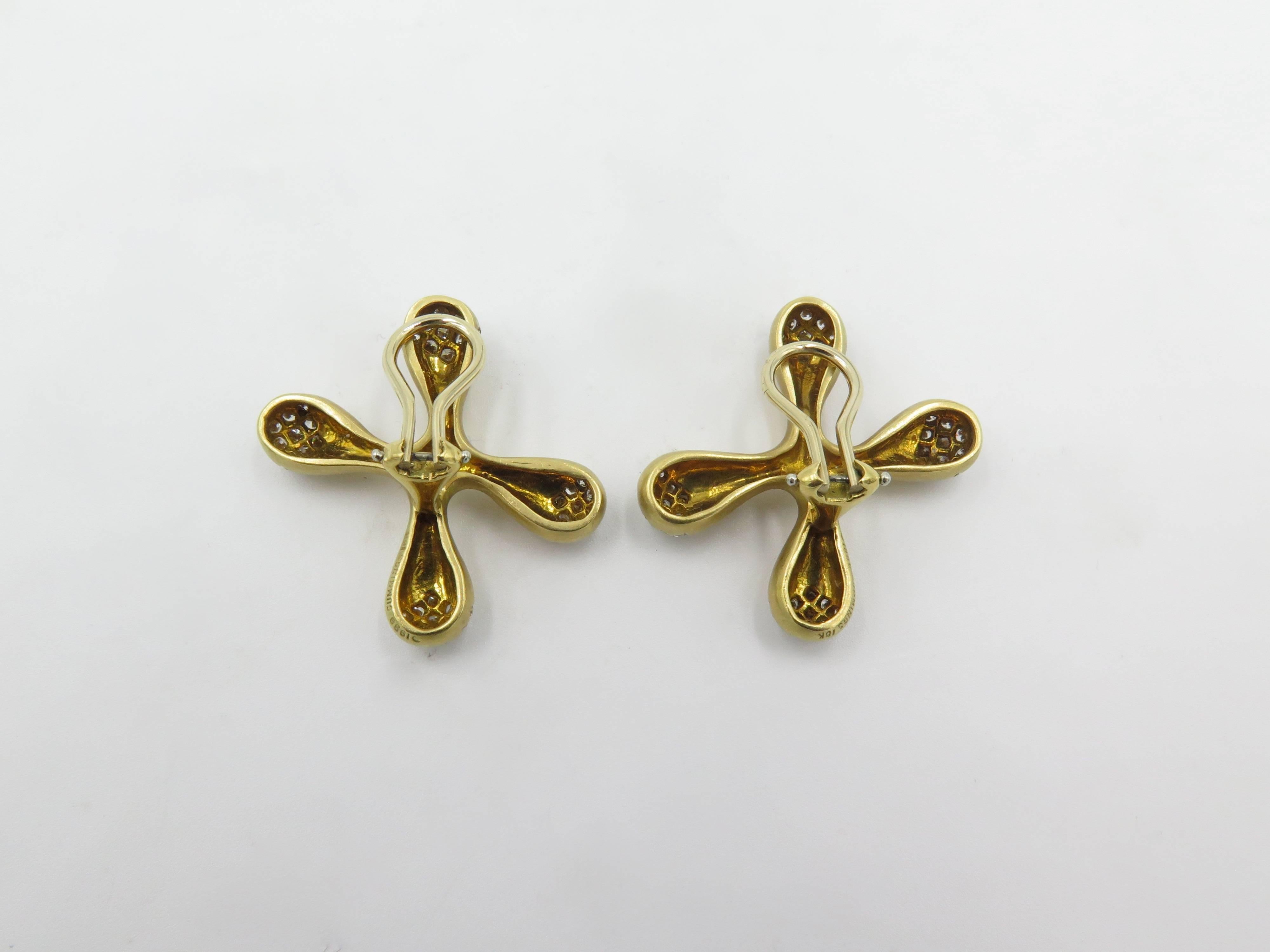 A pair of 18 karat yellow gold and diamond earrings. Angela Cummings. Each designed as a satin finish X motif, enhanced by pave set diamonds. Length is approximately 1 inch. Gross weight is approximately 18.1 grams. Stamped Angela Cummings. 18K,