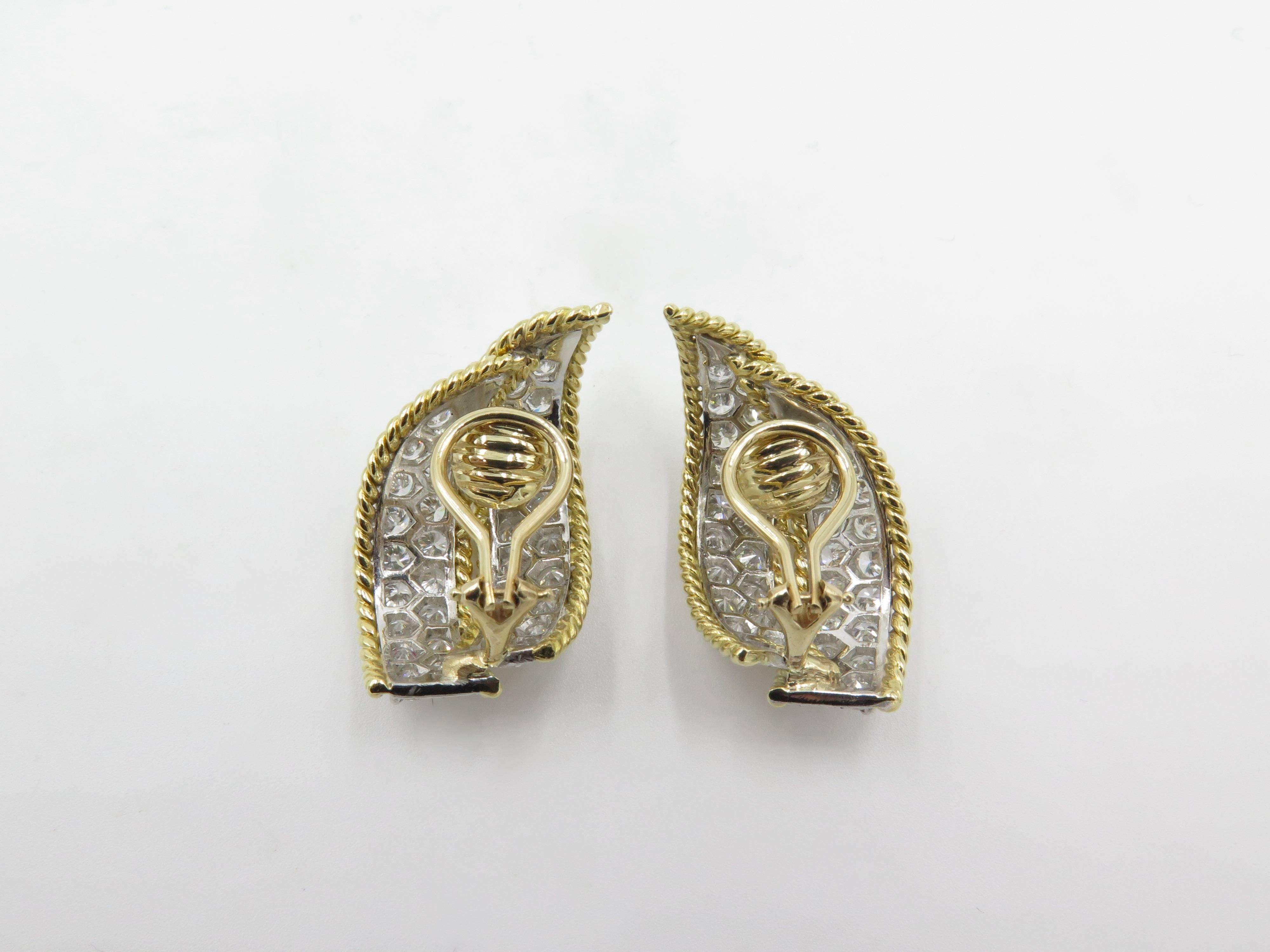 A pair of 18 karat yellow gold, platinum set diamond earrings with 14 karat yellow gold clip.  Circa 1965. Each designed as a pave set diamond scroll, enhanced by gold rope work. Fifty two (52) diamonds weigh approximately 5.20 carats. Length is