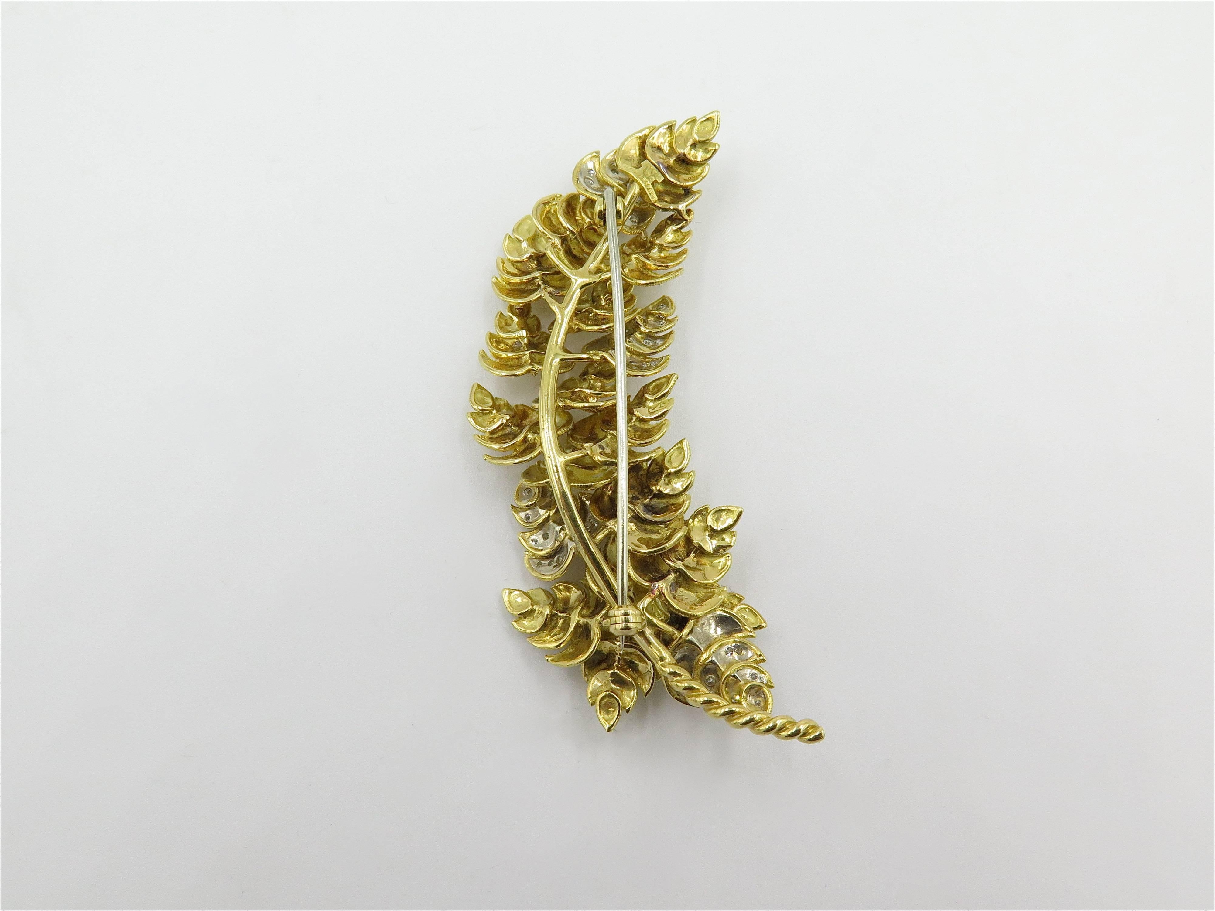 An 18 karat yellow gold and diamond brooch. Tiffany & Co. Italy. Circa 1960. Designed as a textured foliate spray, enhanced by circular cut diamonds. Length is approximately 3 inches. Gross weight is approximately 33.1 grams. 