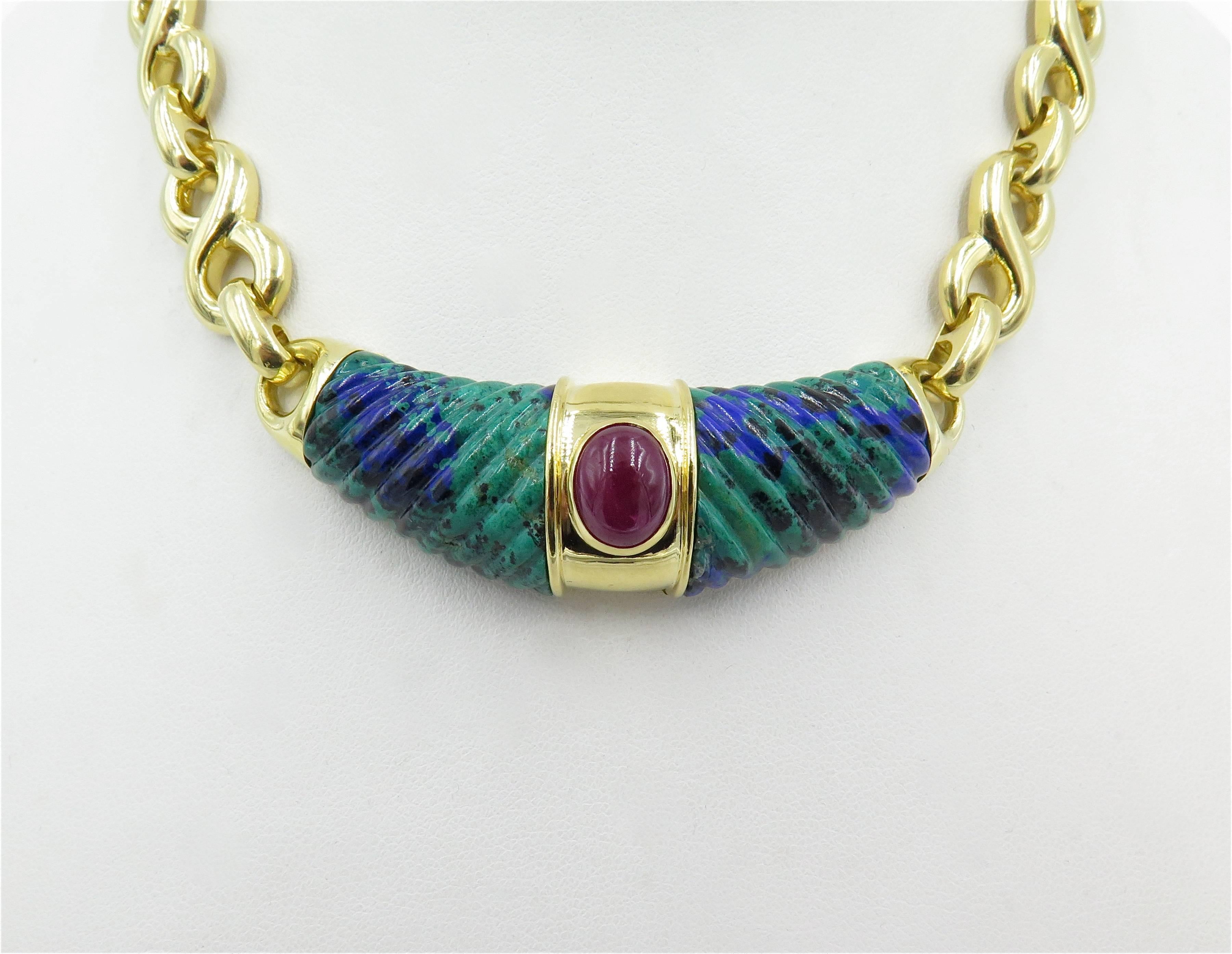 An 18 karat yellow gold, azurmalachite and ruby necklace. David Webb. Circa 1990.  Centering a caved azurmalachite panel, centering an oval cabochon ruby, suspended from a polished figure 8 link chain. Length is approximately 14 inches.  Gross