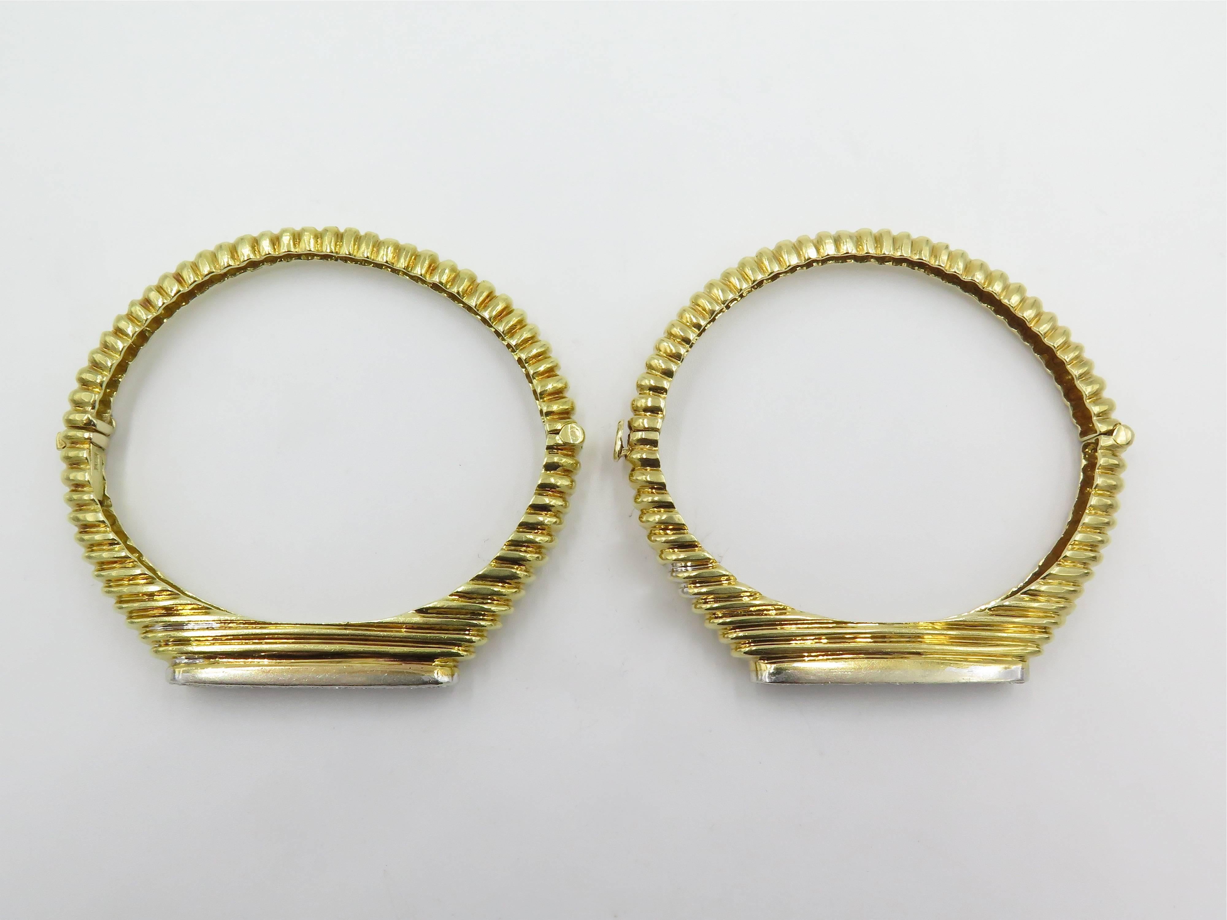 A pair of 18 karat yellow gold and diamond bracelets. Each designed as a fluted hinged cuff of tapered design, centering an oval pave set diamond plaque. Forty four (44) diamonds weigh approximately 2.20 carats total. Each has an inside measurement