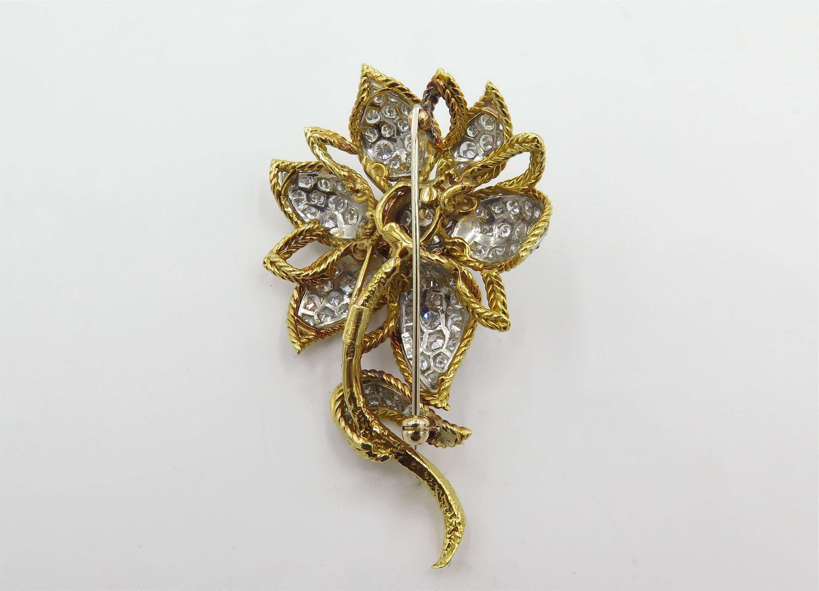An 15 karat yellow gold, platinum and diamond flower brooch. Circa 1960. Designed as a rope work daisy, with pave set diamond petals and leaves. Eighty (80) diamonds weigh approximately 5.00 carats. Length is approximately 2 1/2 inches. Gross weight