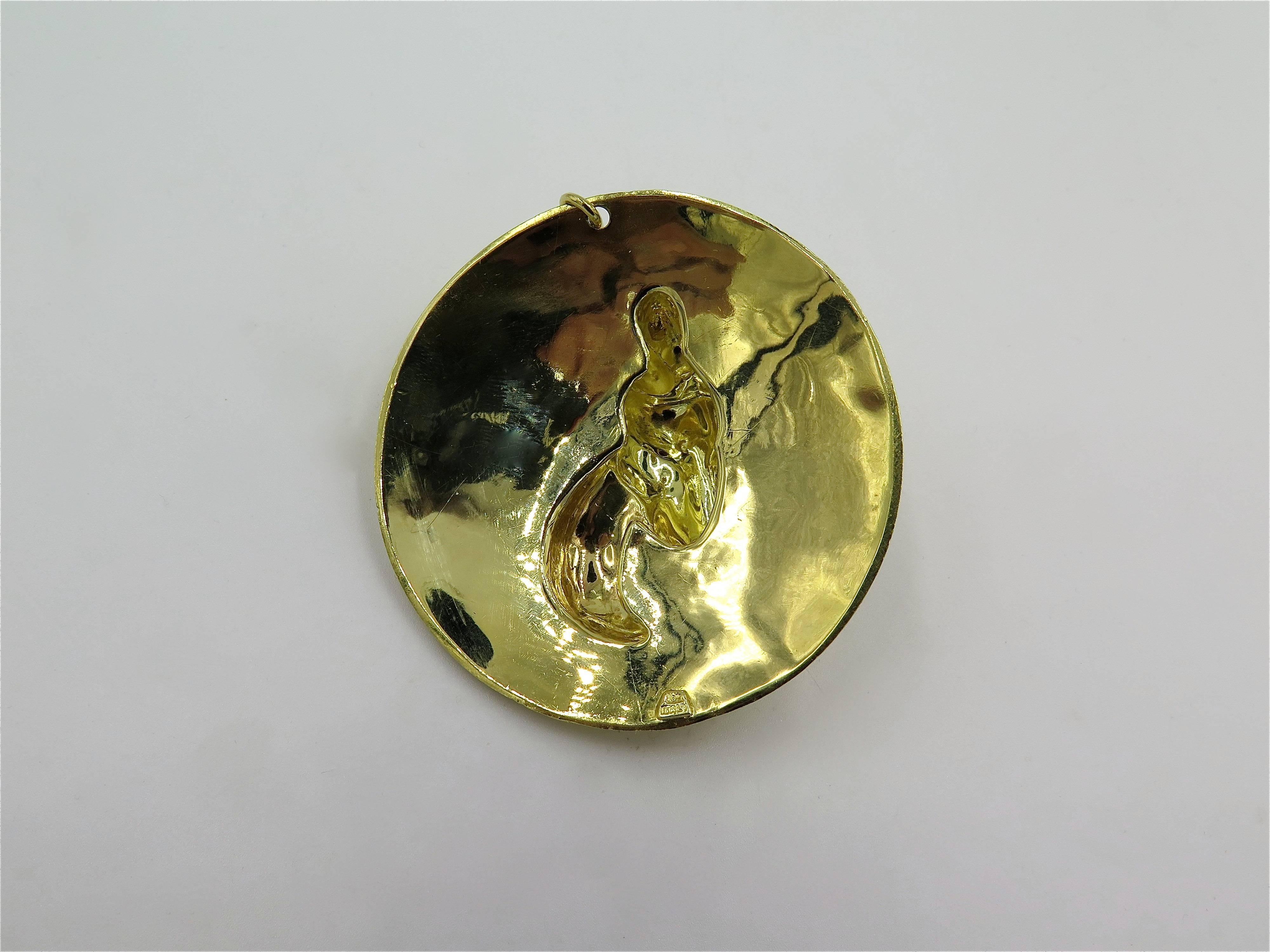 An 18 karat yellow gold pendant. Italian. Circa 1970. Designed as 18 karat yellow gold disk, set with a hammered gold ram, enhanced by circular cut ruby eyes. Diameter is approximately 2 1/4 inches, gross weight is approximately 51.6 grams.