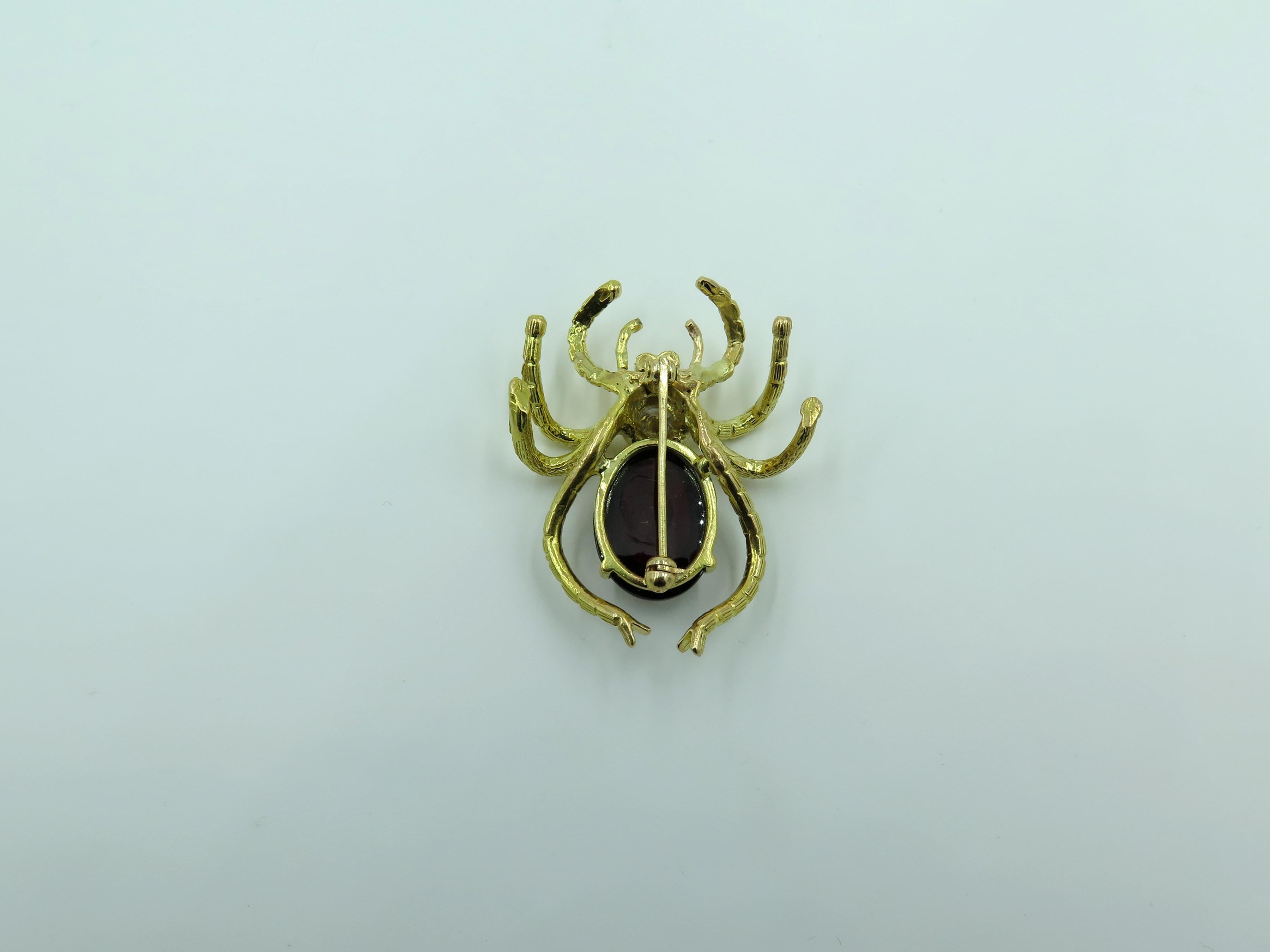 A 14 karat yellow gold, garnet and diamond spider brooch, set with an oval cabochon garnet, enhanced by a circular cut diamond, weighing approximately 0.30 carat, enhanced by small circular cut ruby eyes. Length is approximately 1 1/2 inches, gross