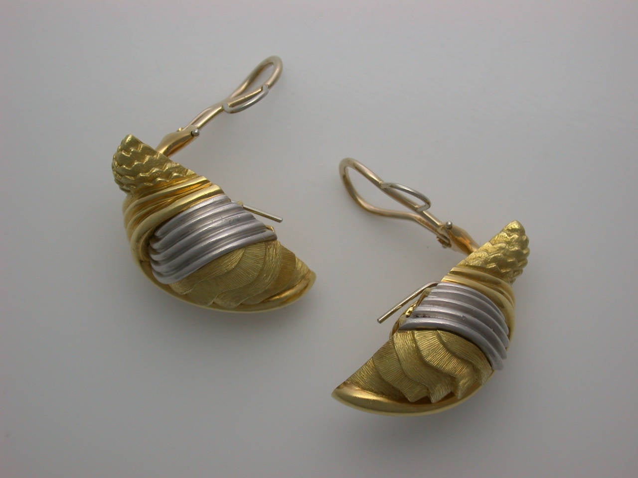 The sculptural earclips designed as snail shapes, with ribbed sweeps of yellow gold and platinum, a tour de force of textures and finishes, can be worn two ways for two different looks, signed Dunay for Henry Dunay, numbered B8714, stamped 750 for