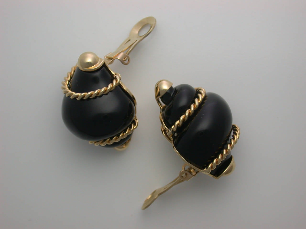 Realistically designed as three-dimensional turbo shells in carved black onyx, wrapped with gold rope and set at the terminals with polished gold caps, well-made with a 