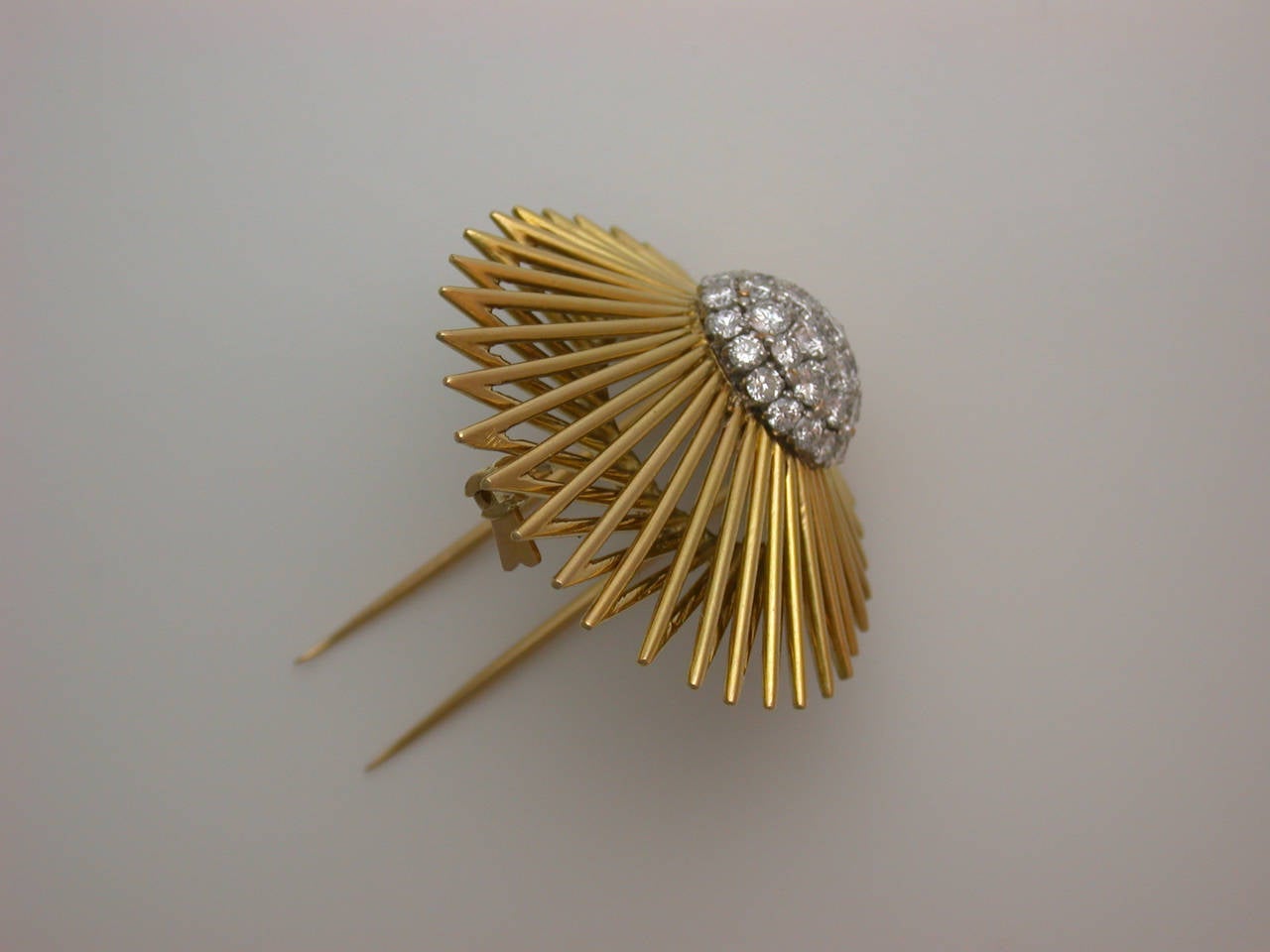 The brooch featuring a platinum and diamond domed element (set with 36 white circular-cut diamonds weighing approximately 2.20 carats total) trailing a dramatic sweep of polished yellow gold rays like a meteor shooting across the sky, signed Van