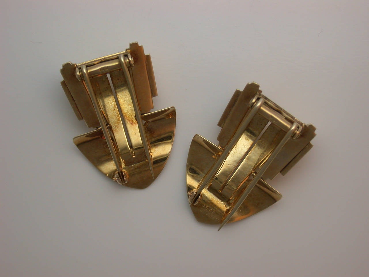 Of typical architectural form, the polished yellow gold dress clips with strong style and simple, modern lines of Machine Age design, signed Tiffany & Co., stamped 14K, hinged double pin clip backs and safety catches, measuring approximately 1 3/8