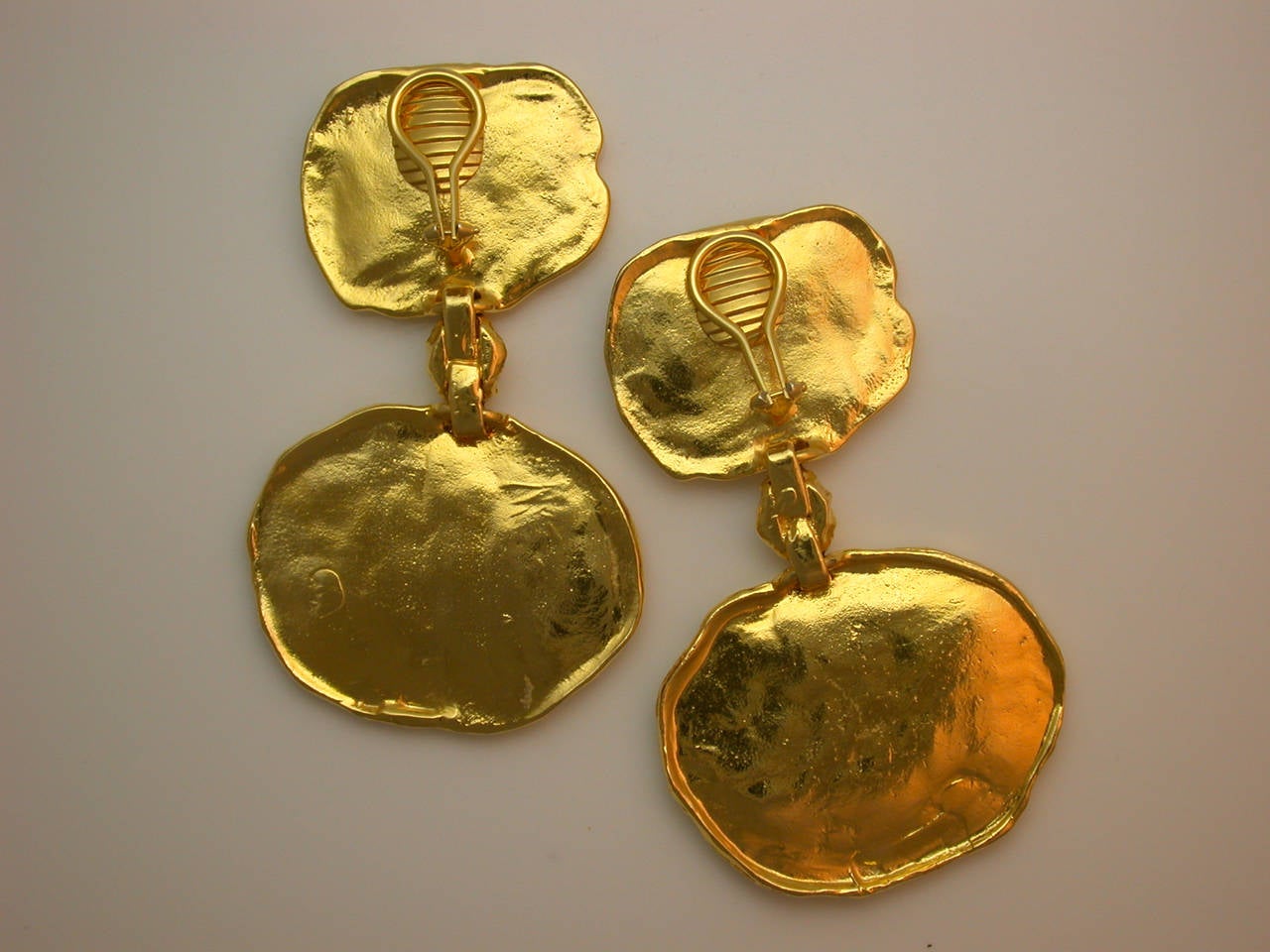 Designed as heavily textured coin shapes clipped to the ear, flexibly joined by nugget-shaped elements to larger coin shapes similarly textured, mounted in sterling silver plated with 24kt yellow gold (